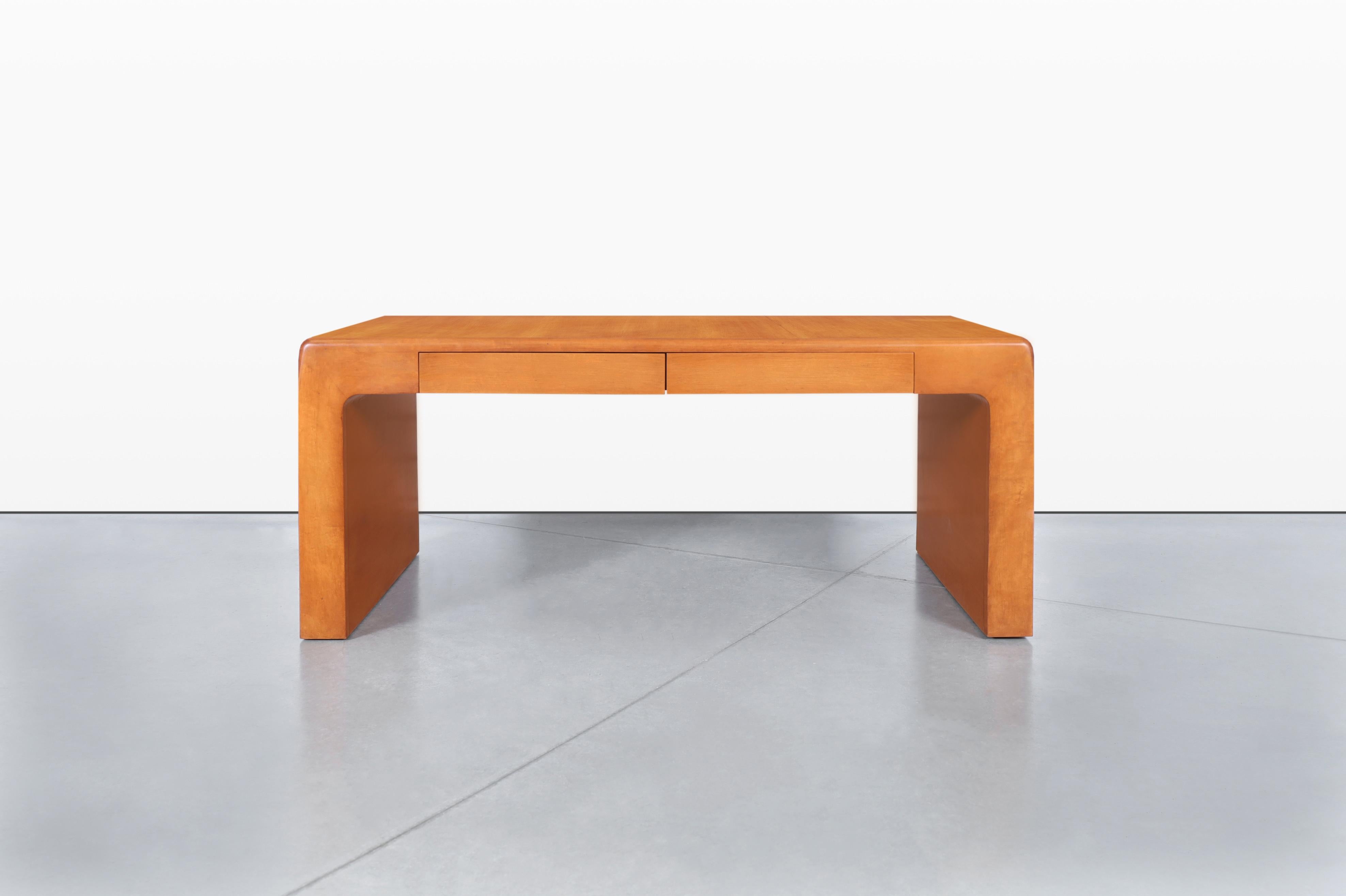 Introducing a beautiful vintage executive desk, expertly designed in the United States during the 1970s, that seamlessly blends functionality with artistic flair. This desk showcases a striking waterfall edge on both ends, creating a smooth profile