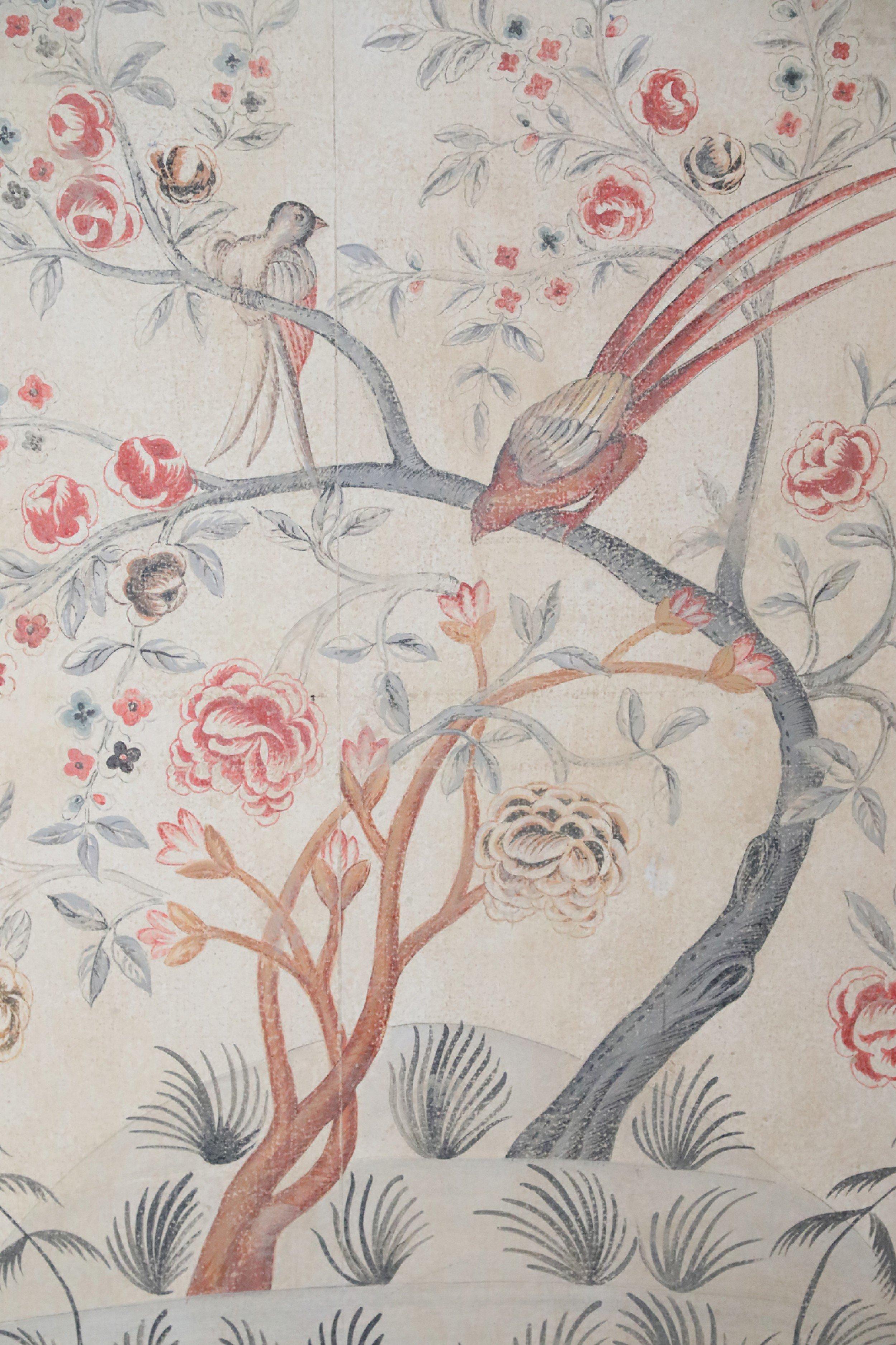 Vintage (20th century) panel with a ground that mimicks antique parchment and a painting of blue-grey and teracotta-colored undulating trees blooming with florals and housing two birds, one of which is displaying dramatic red feathers. The painting