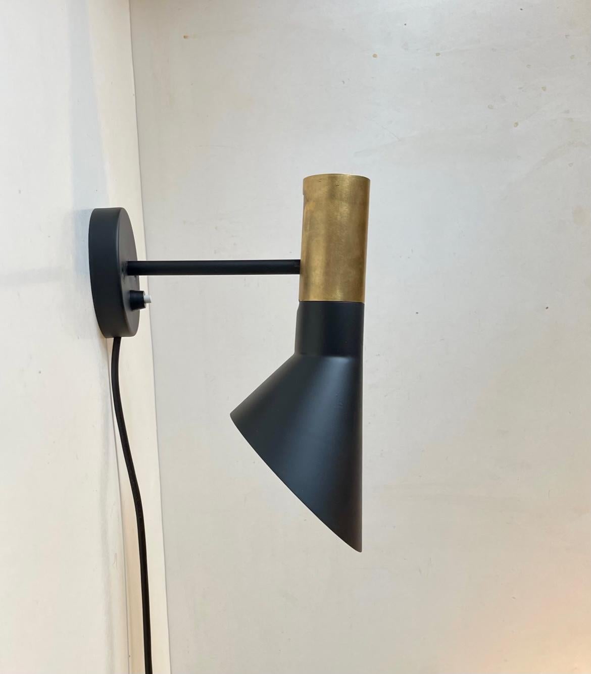 A rare version of the AJ visor Wall lamp. Designed by Arne Jacobsen in 1960 for Royal SAS Hotel in Copenhagen. This particular example features an exposed brass top. Only the first series were partially made from brass. The shade adjust up or