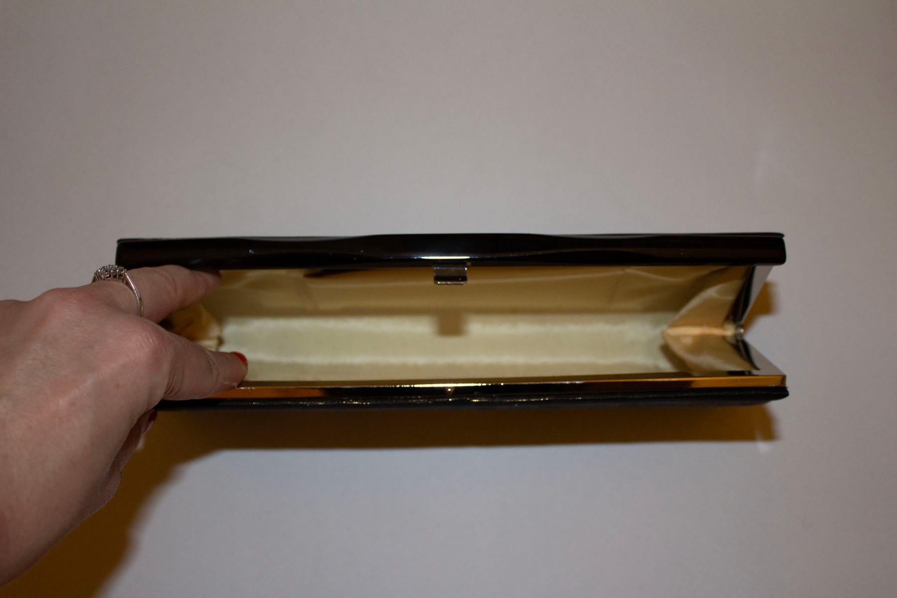 Eine atemberaubende Vintage-Cutch-Tasche in Schwarz und Gold aus seltenem Saga-Nishiki-Brokat  Die Tasche hat zwei Innenfächer und einen schwarzen Zentralverschluss. 
Abmessungen: Breite 10 1/2'', Höhe 5'', Tiefe 2''