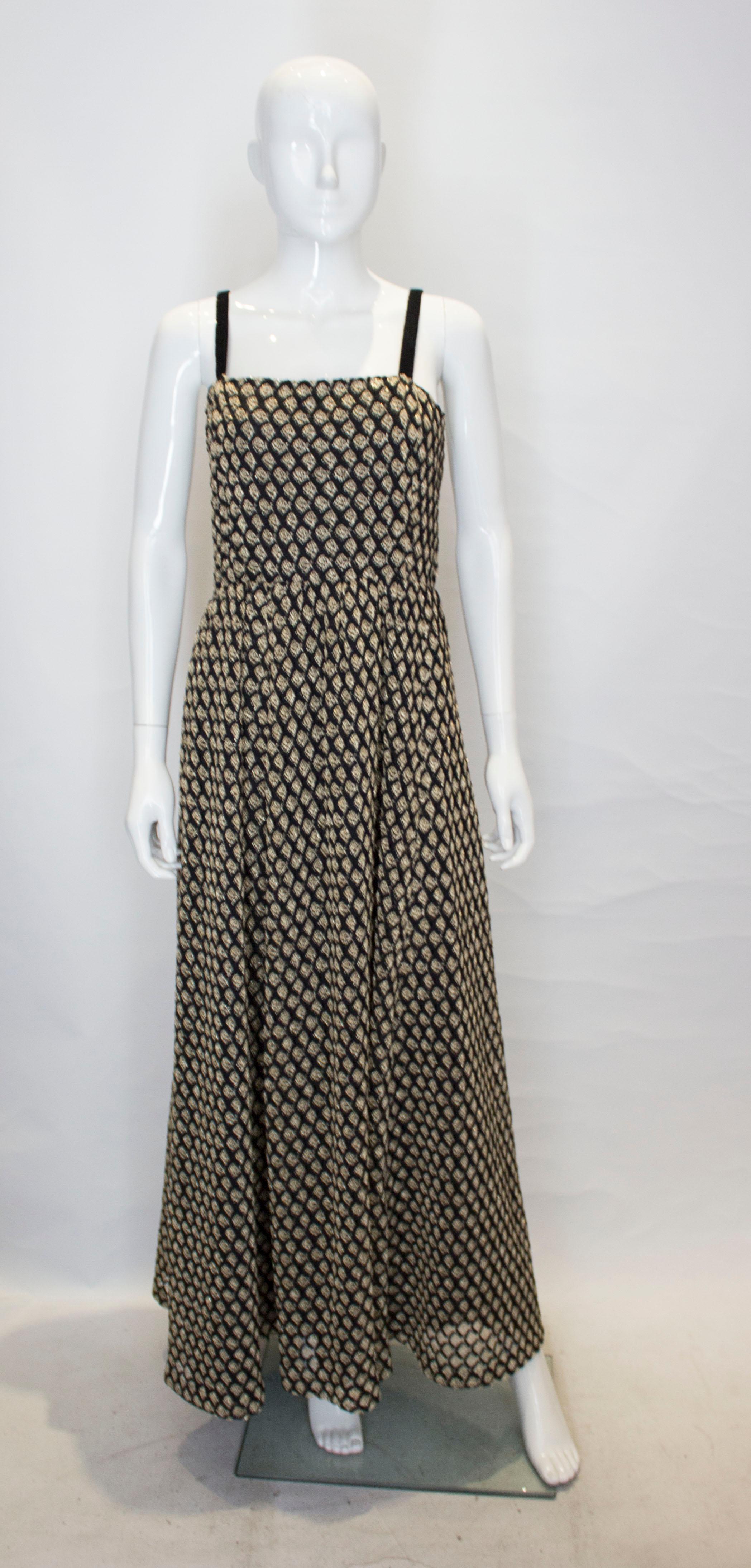  A chic headturning dress in black and gold.  The dress is in a black and gold mesh like fabric with  a black lining. It has black velvet shoulder straps and has gathering at the waist.