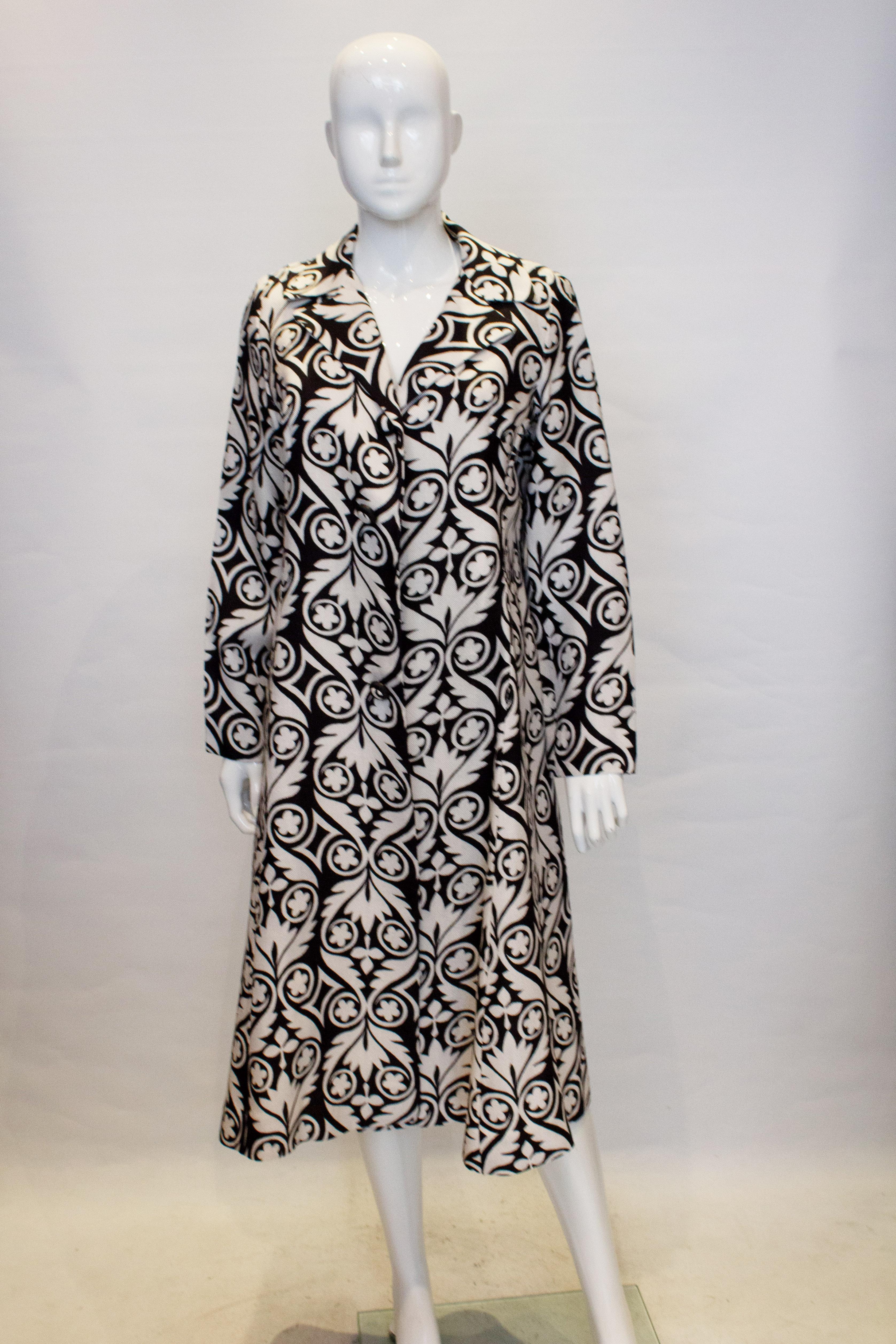 A stunning vintage duster coat  in a graphic black and white print. The coat is in a linen like fabric with a cut away collar. Marked a size 40.