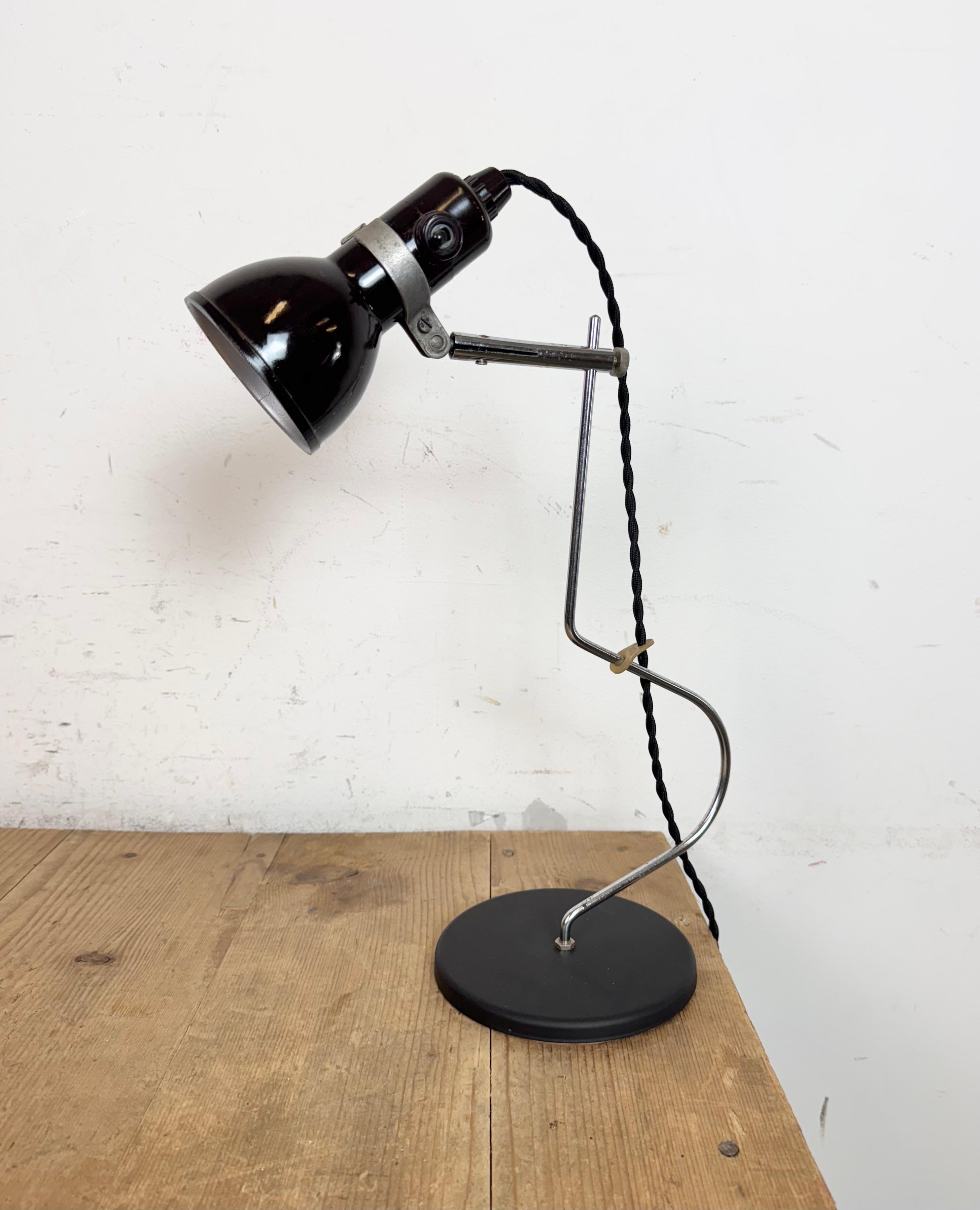 Cette lampe de table réglable a été produite dans l'ancienne Tchécoslovaquie dans les années 1970. Elle comporte un abat-jour en bakélite avec interrupteur d'origine, un bras chromé et une base en fer. La douille est compatible avec les ampoules E14