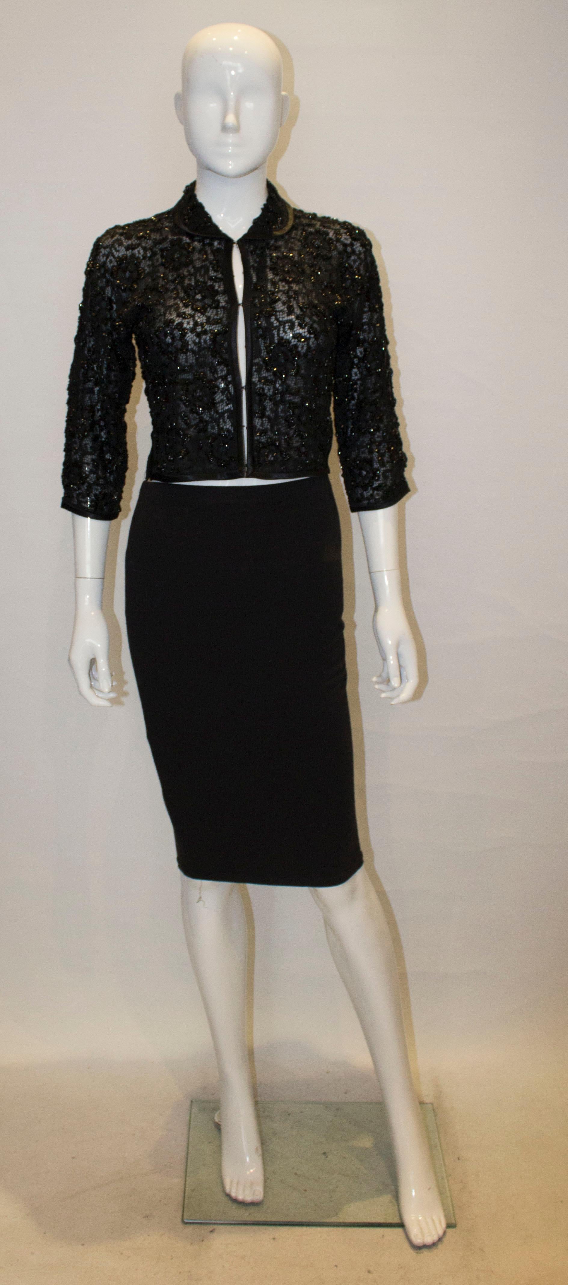 A chic vintage black beaded evening jacket , with a ribbon trim collar and crepe lining. The jacket has two 2'' side slits with hook and eye fastening.