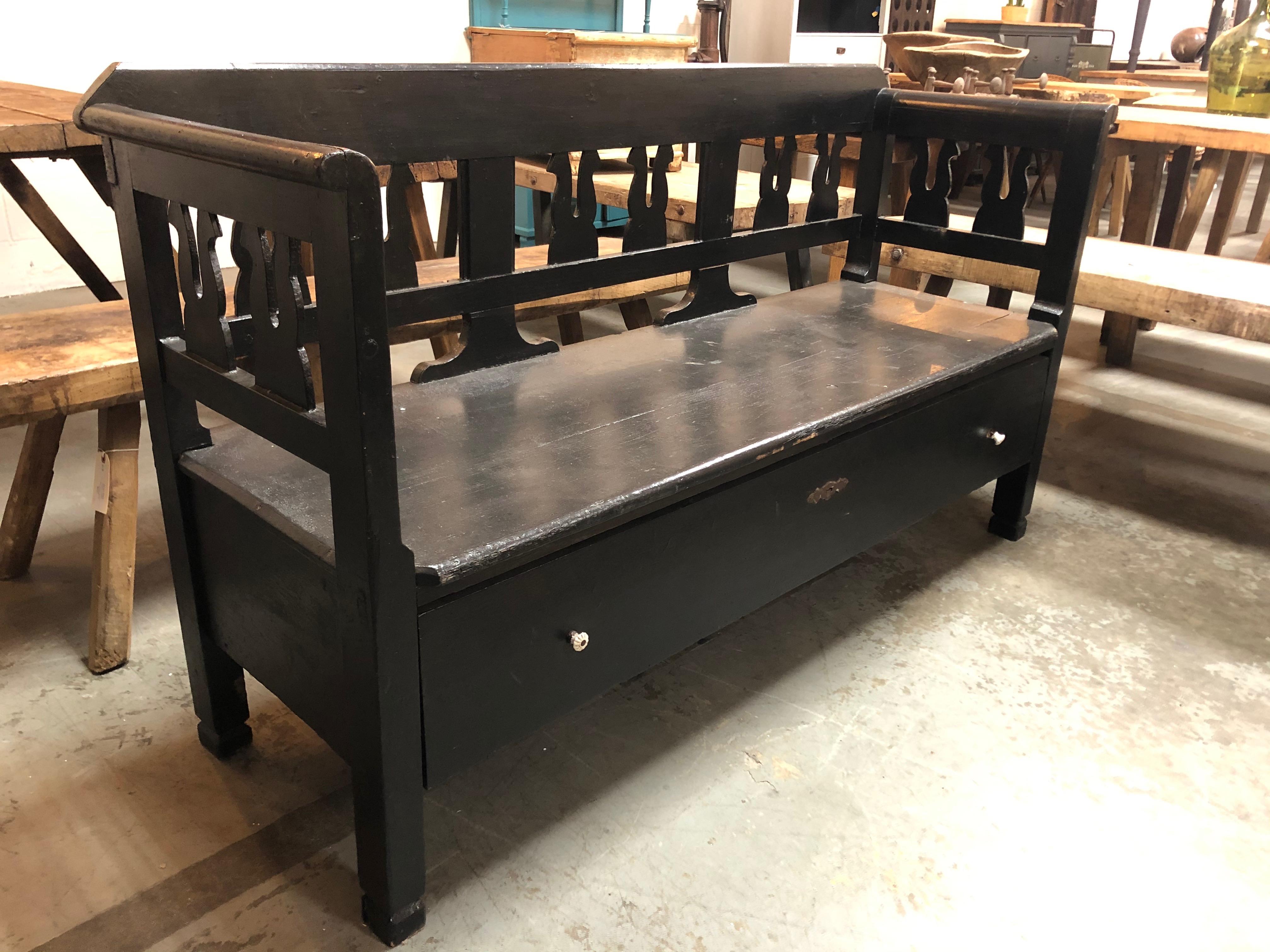 Antique bench from Europe with a storage drawer to keep linens or footwear. Detailed wood carving wraps around the back and sides, adding character to any space or entryway.