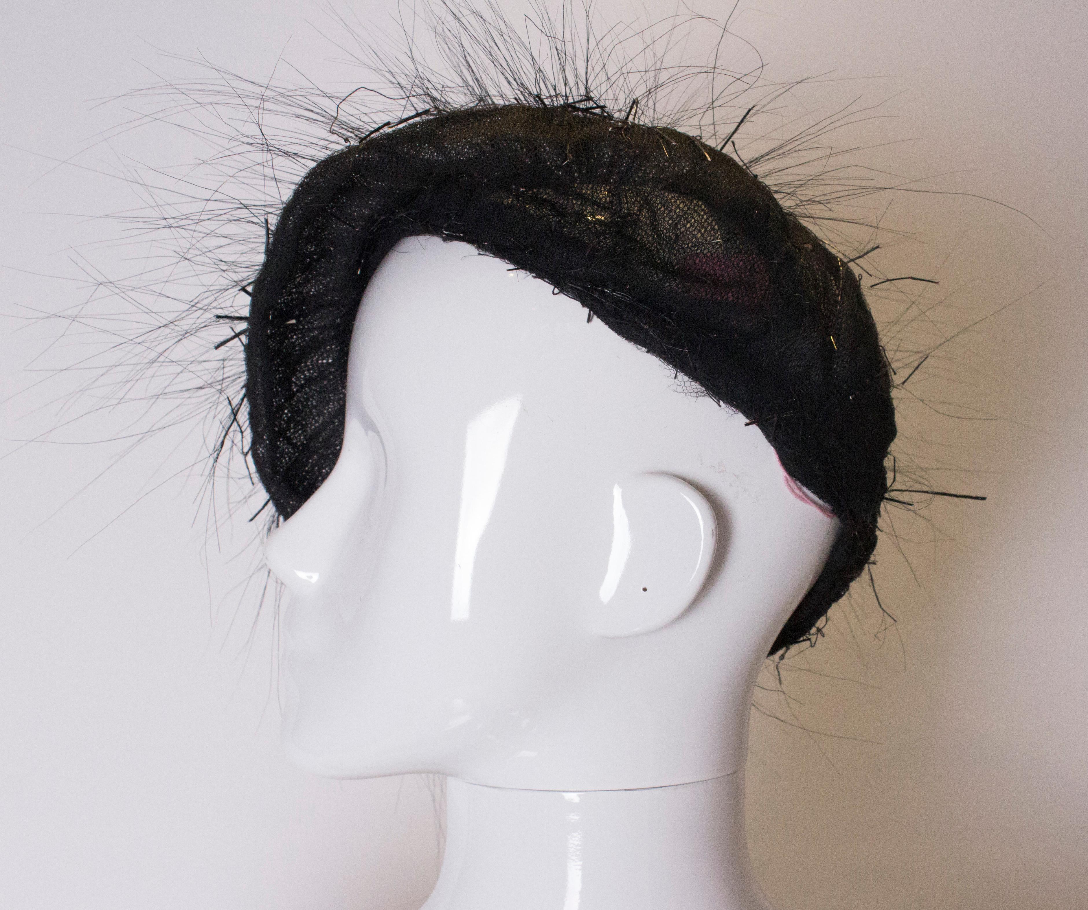 An unusual and chic black beret. The beret is made of black net with a black satin swirl at the top , with black feather 'spikes' radiating out.