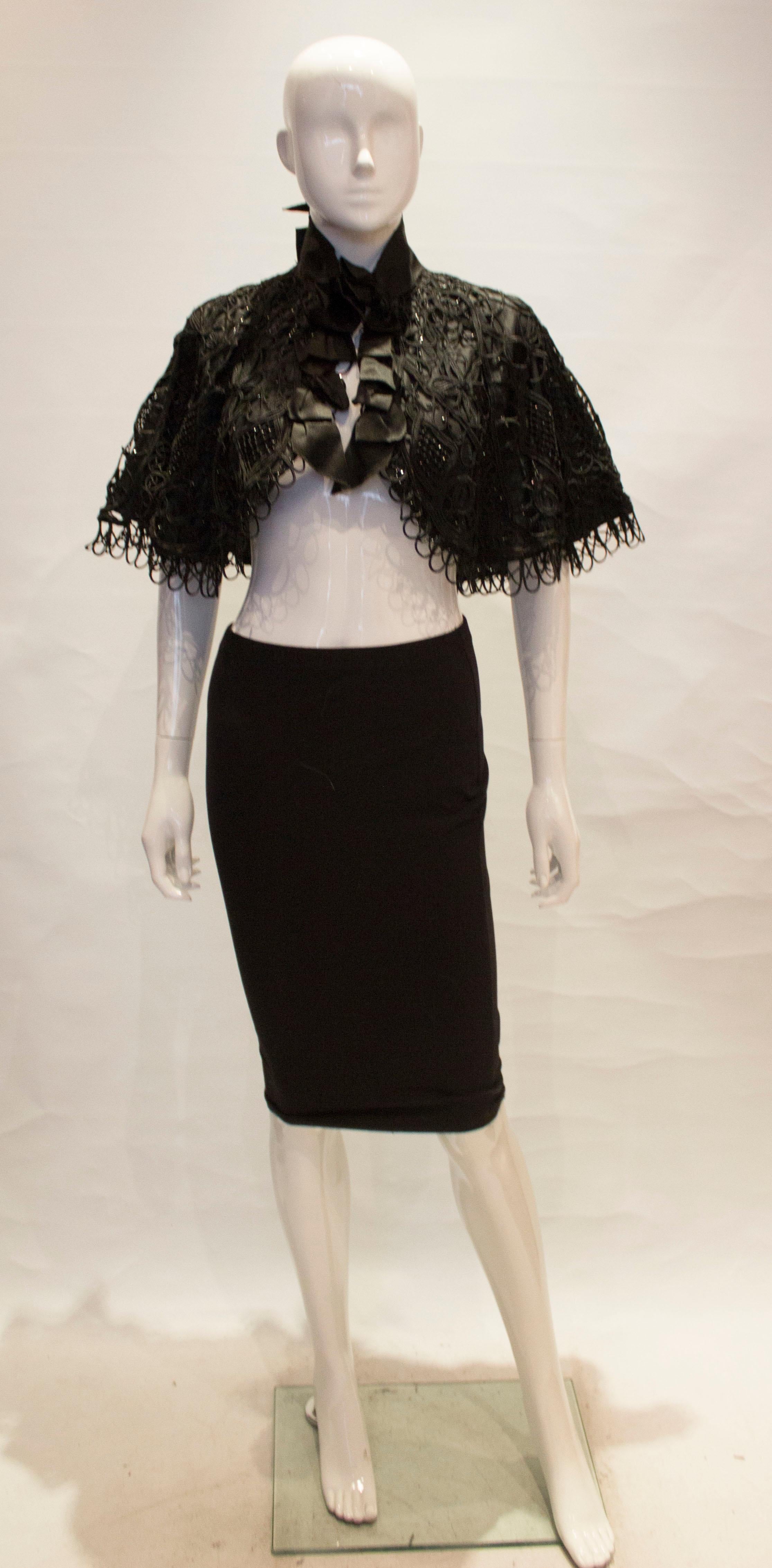 A great addition to your party wardrobe, this vintage black cape has a stand up collar with bow detail. The outer layer has bead and lace detail and it is silk lined.

Measurements: shoulder to shoulder 22'', length 18''