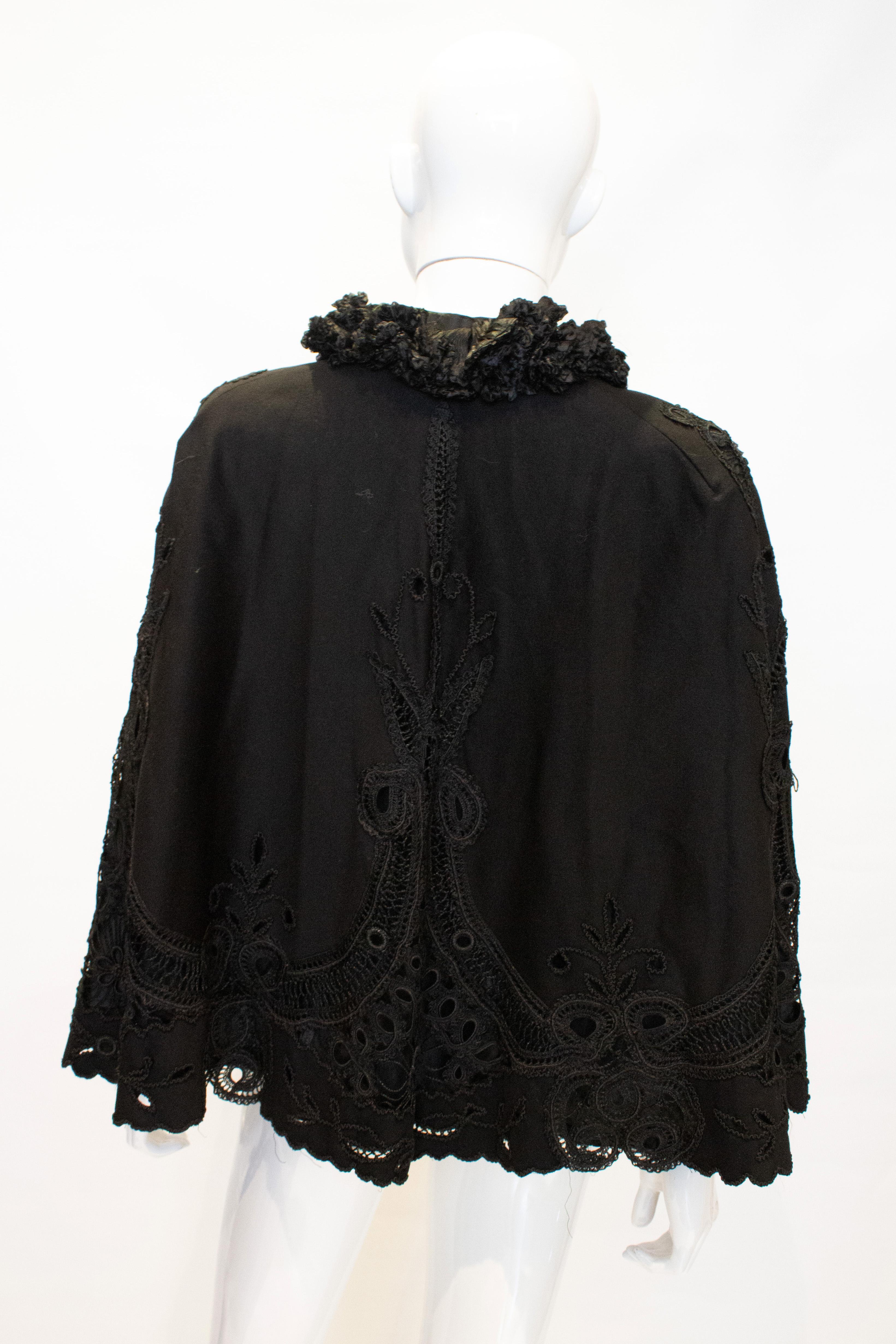 A chic vintage black cape with embroidery detail, and frill at the neck.  The cape is lined.
Measurements: Shoulder to shoulder 18'', ;length 25''