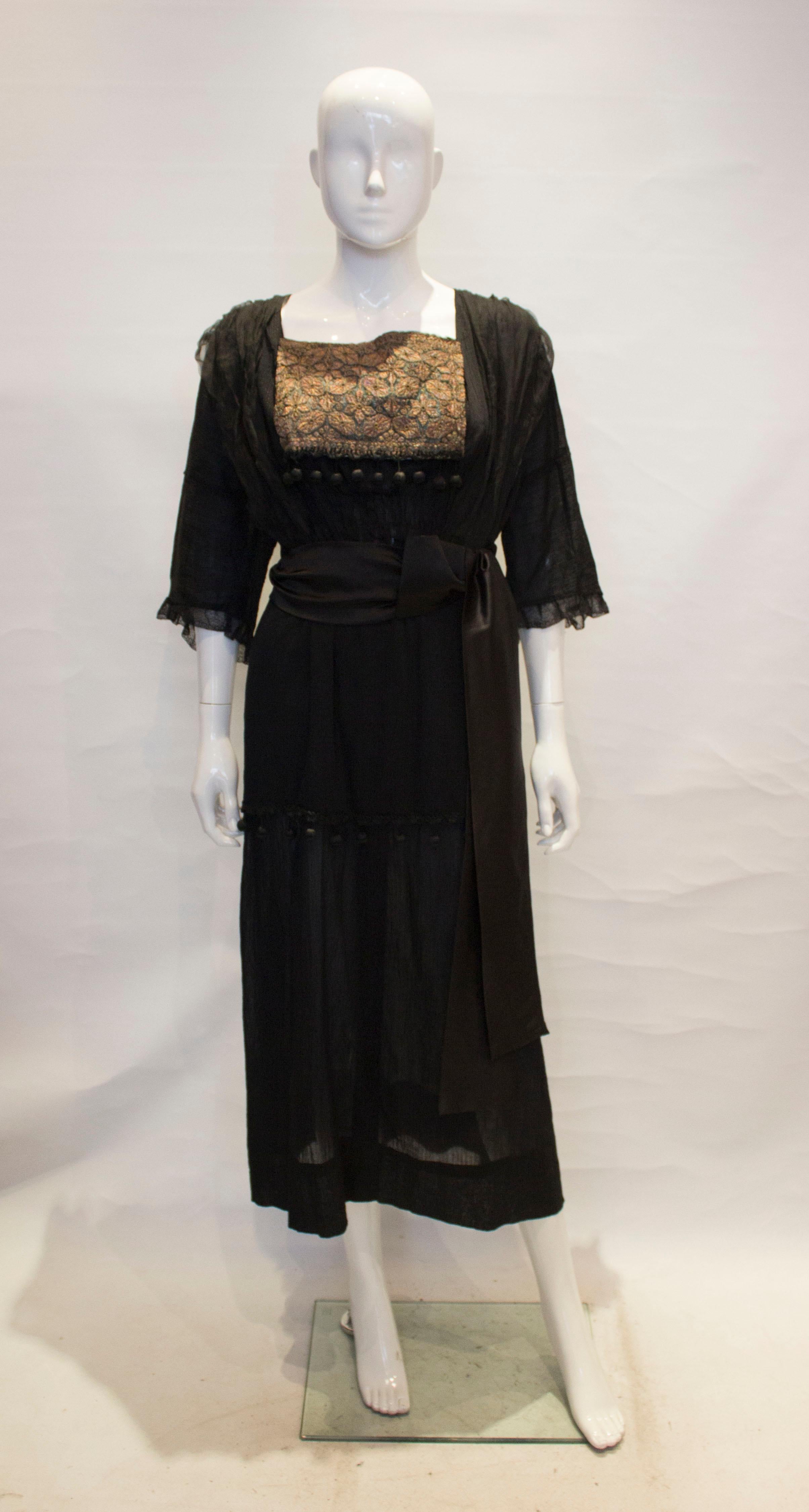 A very vintage cocktail/dinner dress.The dress has a square neckline, front and back. with an embroidered patch front and back. It has elbow length sleaves and a half layer of over skirt.