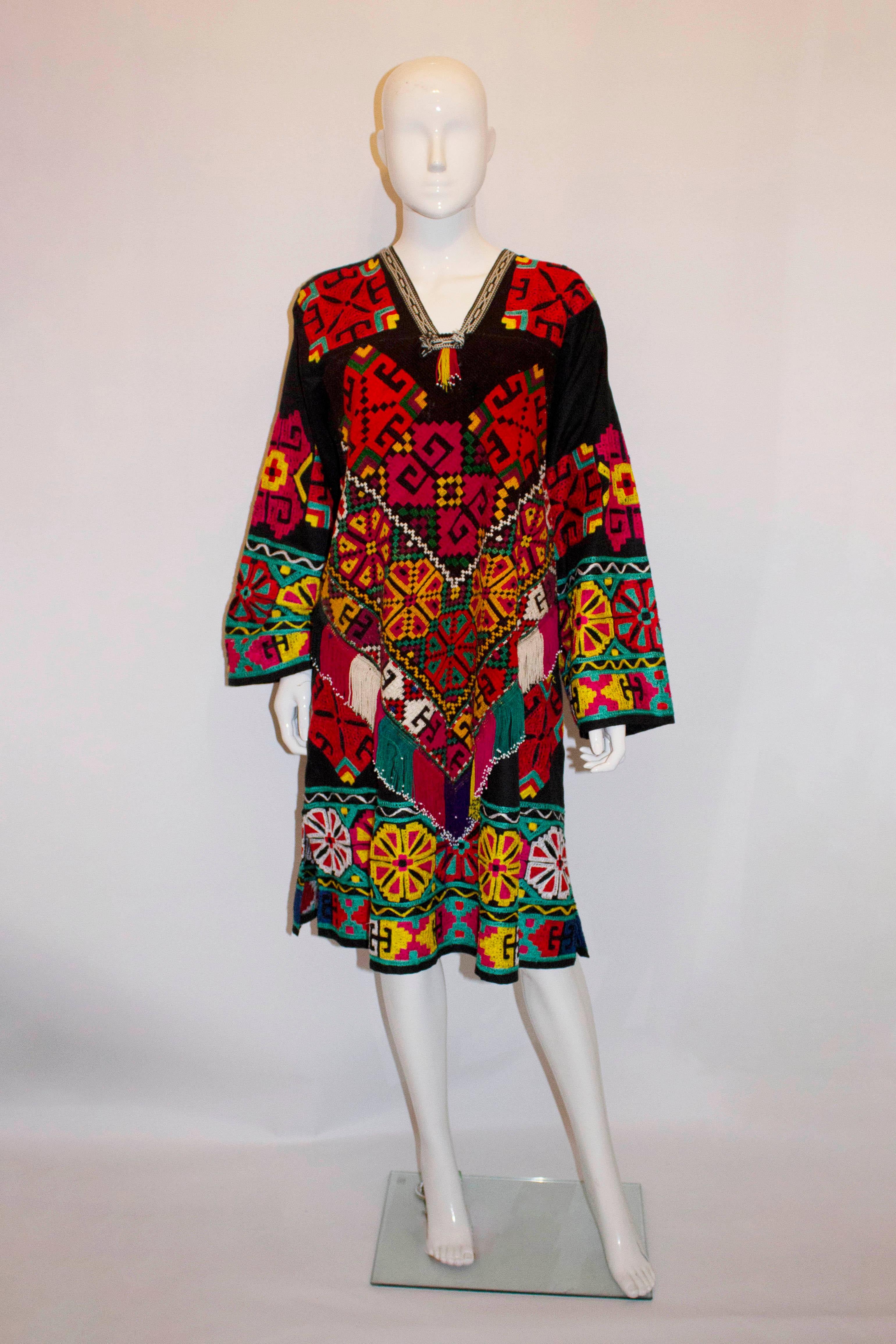 A wonderful vintage cotton kaftan with colourful embroidery. The black cotton kaftan is heavily embroidered front and back , with fringing , a v neckline and 8'' slits on the side. 

Measurements : Bust up to 54'', length 42''