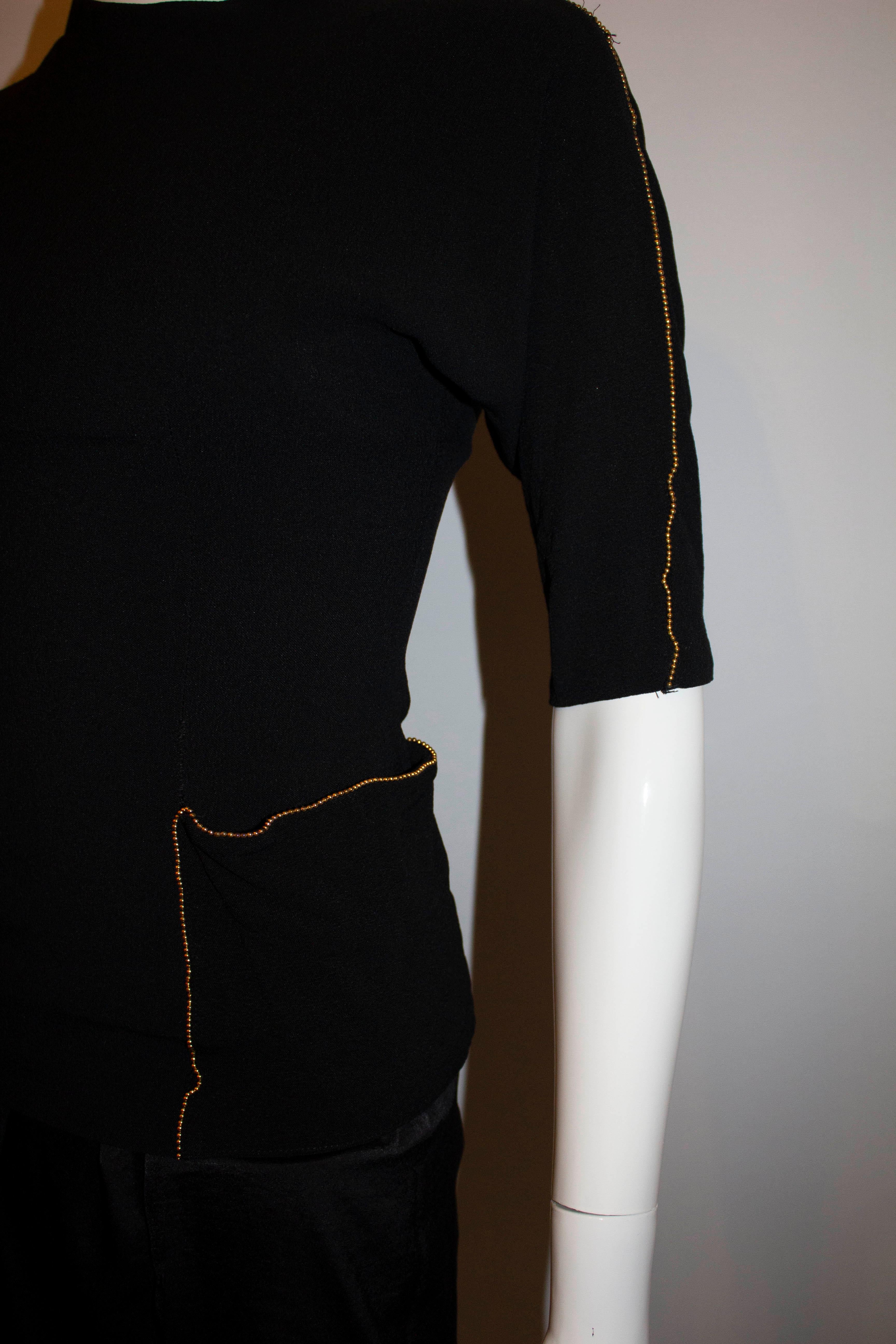 A chic vintage top in black crepe by Richey Jr.  The top has a back central zip with gold beading along the arms and on the pocket detail.  The two pockets have popper fastenings so they dont 'drop'.
Measurements : Bust 35'', length 23''