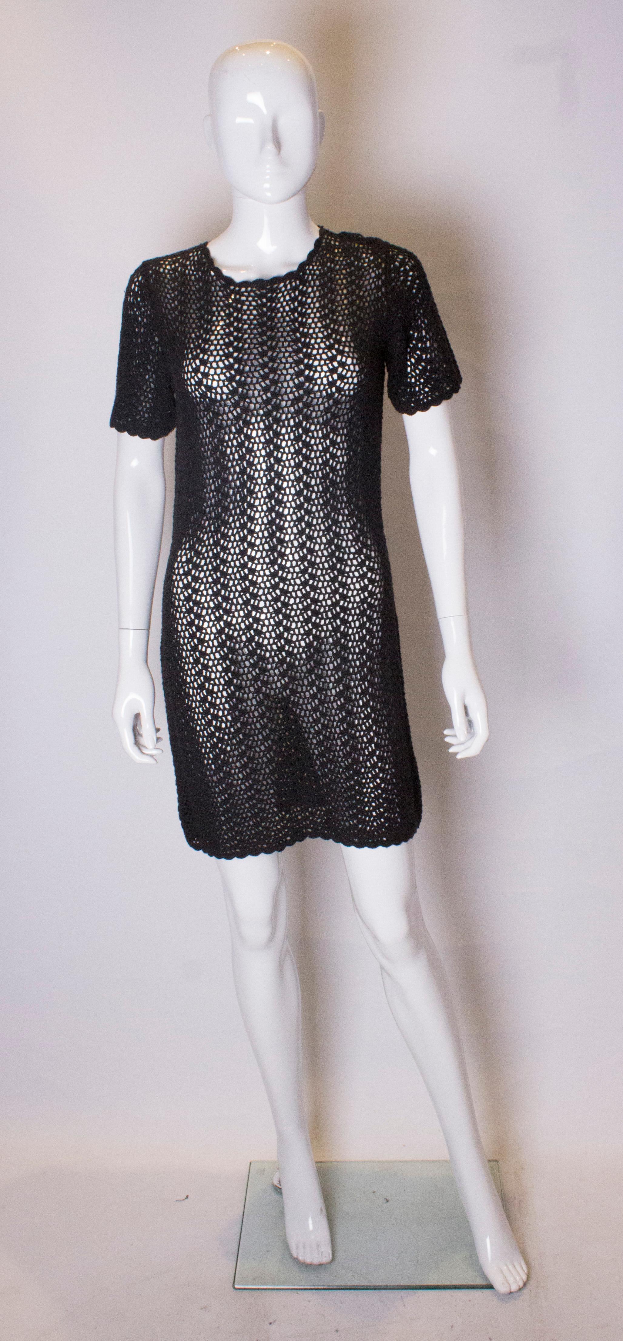 A chic crochet vintage party dress. This black mini dress has cap sleeves and a scallop edge on the hem, neckline and arms.