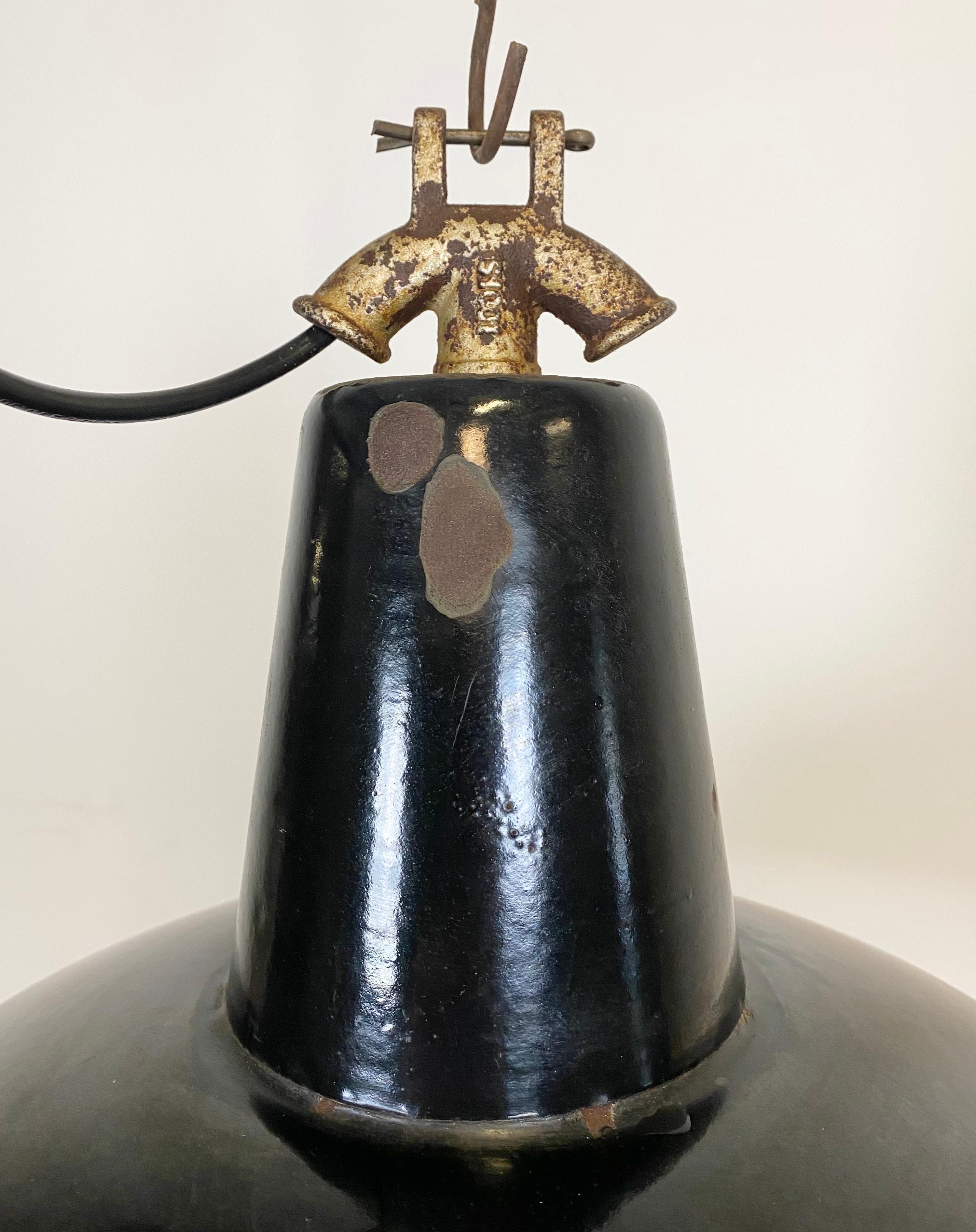 Industrial pendant light from former Czechoslovakia, previously used in a factories. Made from enamelled metal. Black outside, white interior. Interesting cast iron top. New porcelain socket for E 27 lightbulbs and wire. The weight of the lamp is 2