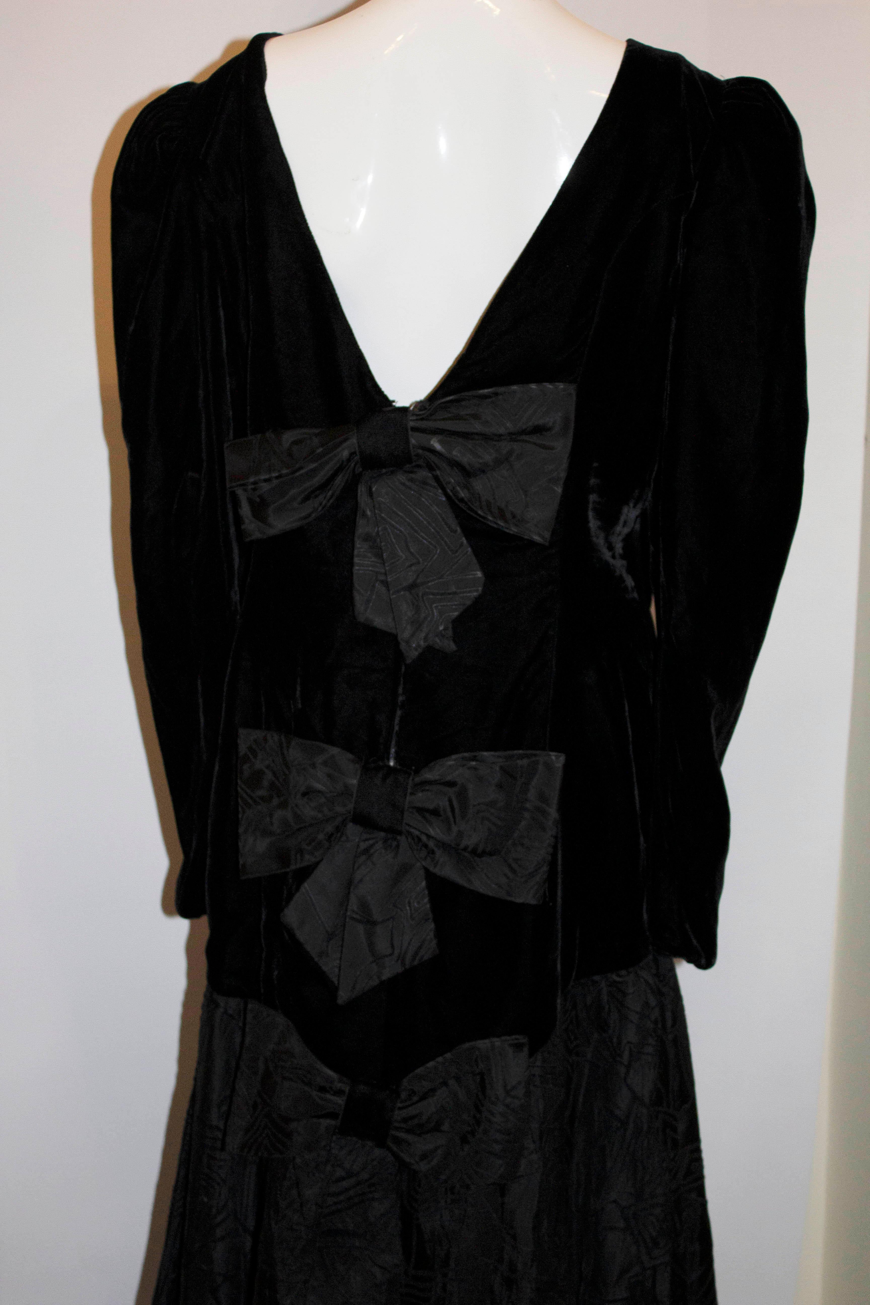 Ein wunderschönes Abendkleid aus den 1980er Jahren. Das Kleid ist schwarz mit Schleifen auf der Vorder- und Rückseite und einem Taftrock mit Netz darunter. 
Maße: Büste 38'', Länge 53''

