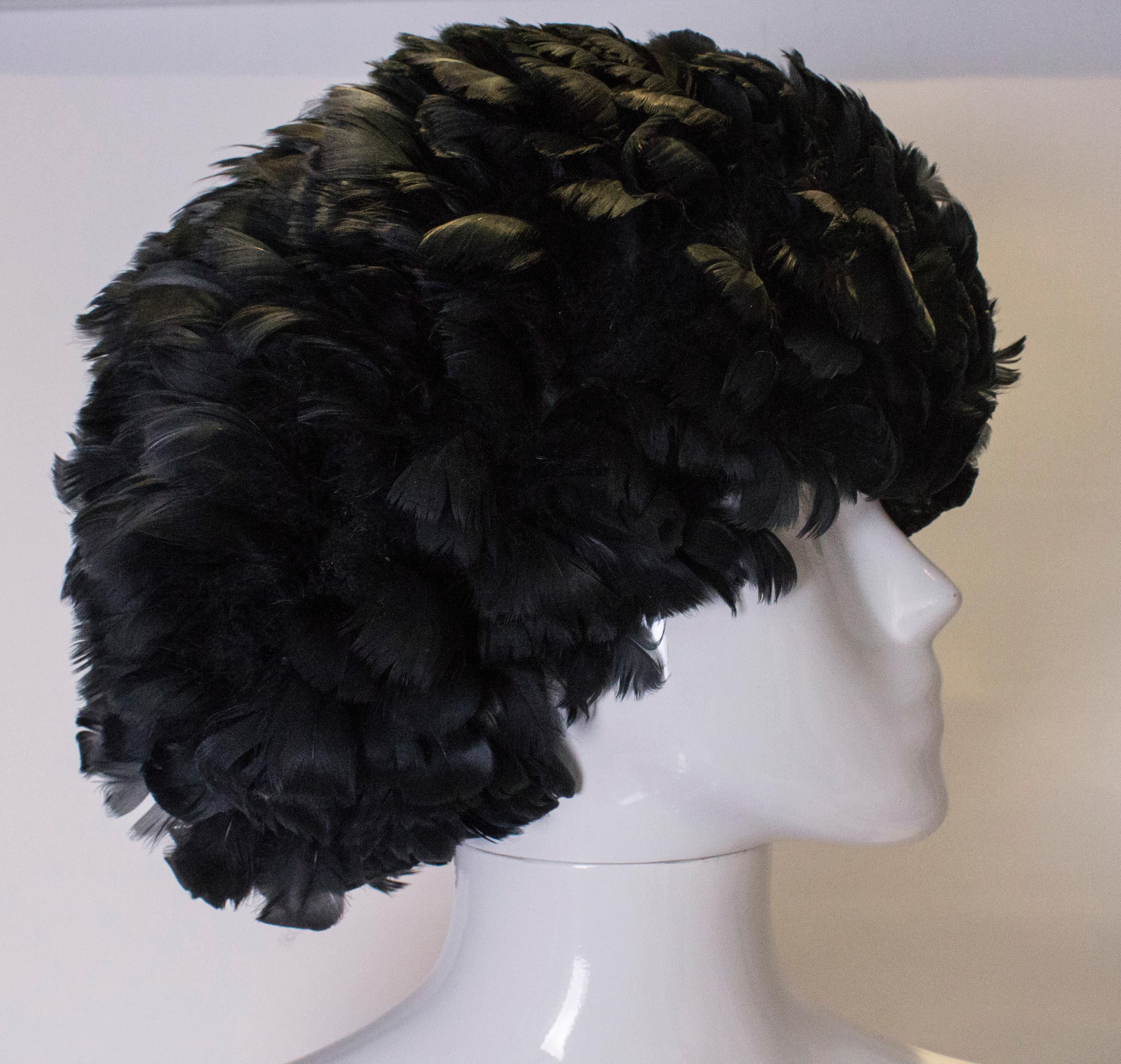 A fun and easy to wear black feather hat. The hat has a soft, pliable mesh base and so can be easily packed, it is covered with an abundance of black feathers.