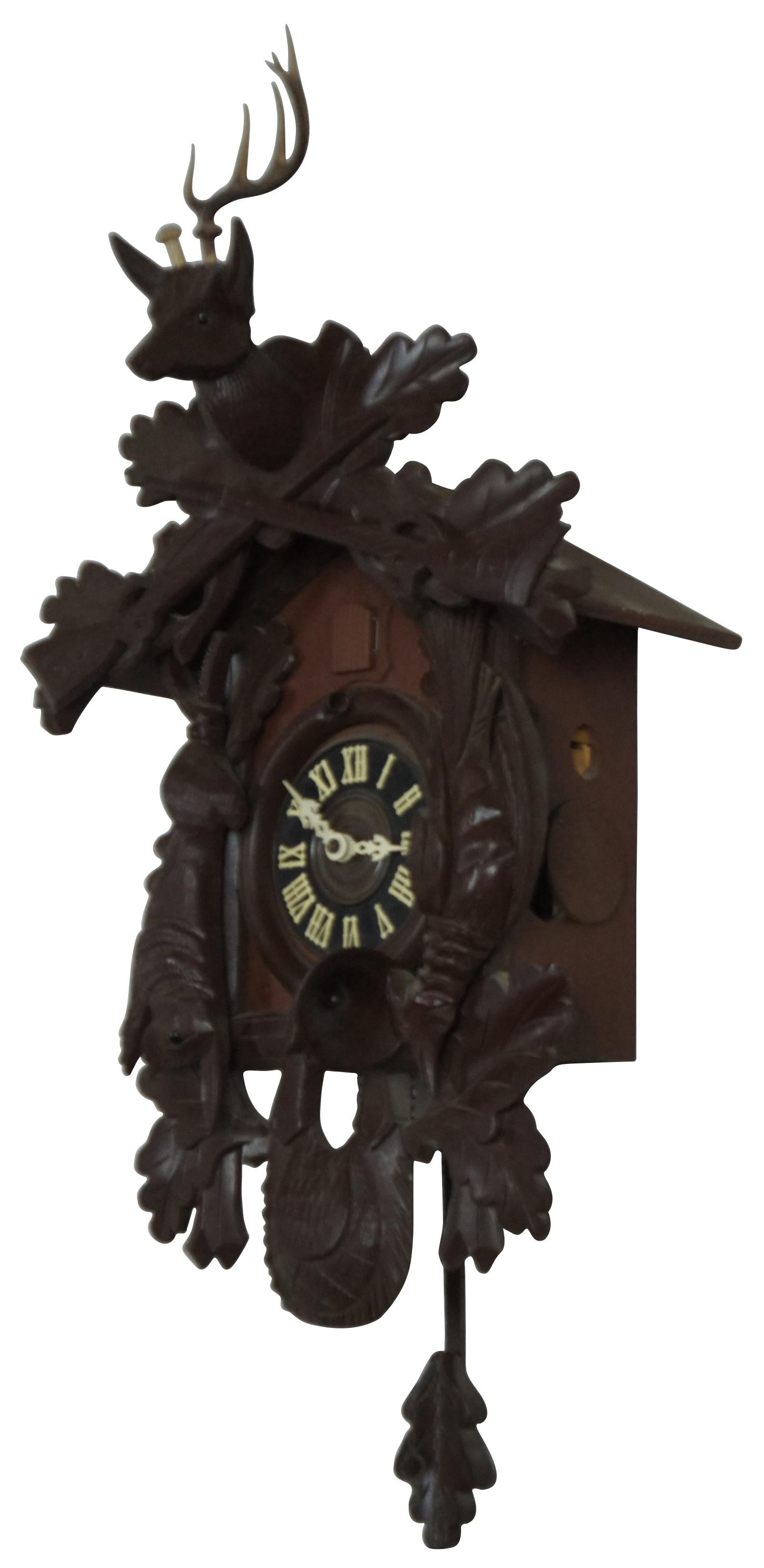 Vintage German black forest cuckoo clock with Regula works, decorated in a hunting motif featuring a game bag, forest leaves, rabbit, bird, two guns, deer head, white and blue cuckoo, and a leaf shaped pendulum. Includes two pine cone shaped
