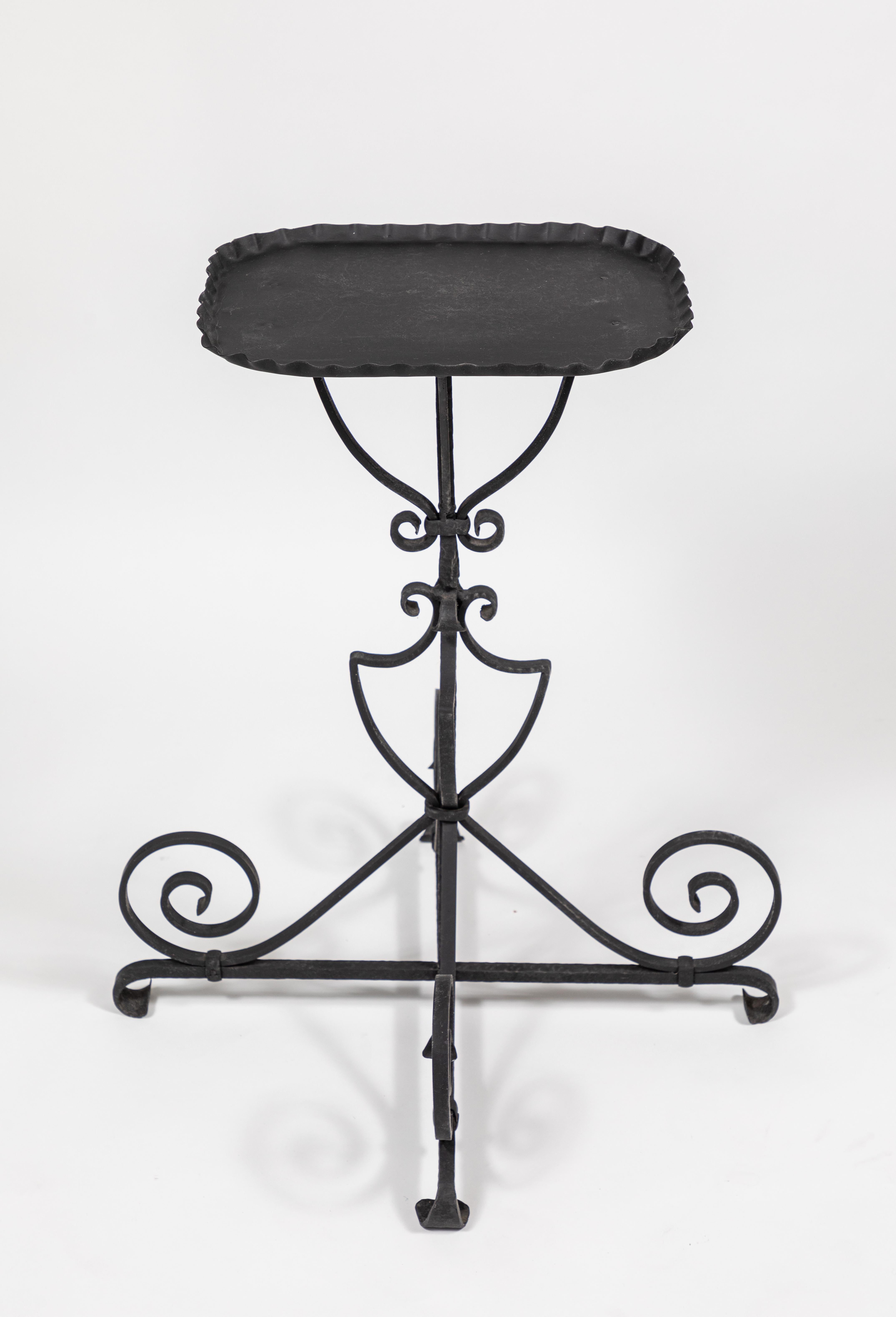 Vintage iron side table featuring a sculptural and graceful scrolled base.

New black painted finish

Overall dimensions: 23