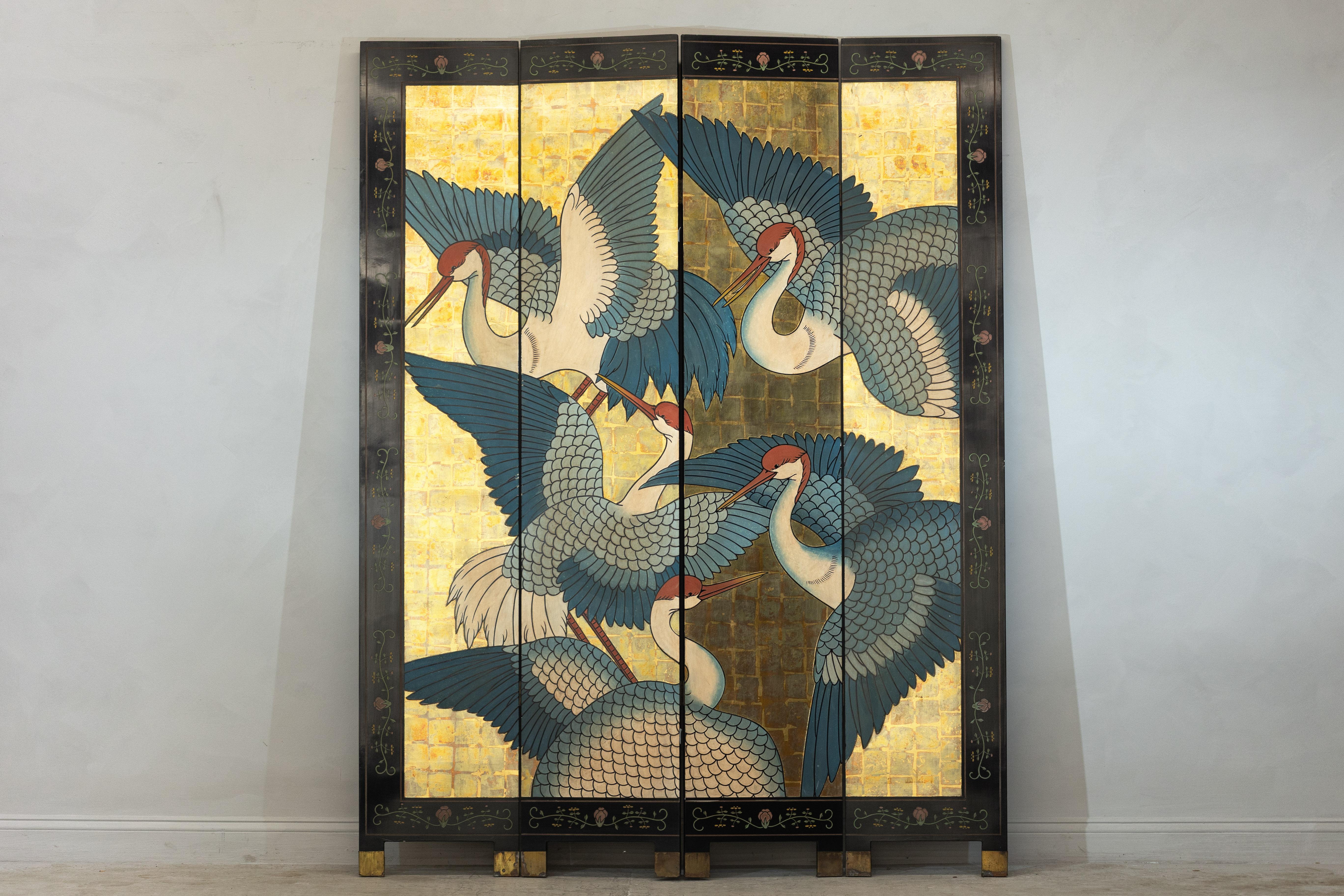A striking display of artistry, this Chinese lacquered folding screen showcases a mesmerizing composition of red-crowned cranes in flight against a golden backdrop. The four-panel construction features a dynamic arrangement of cranes, their detailed