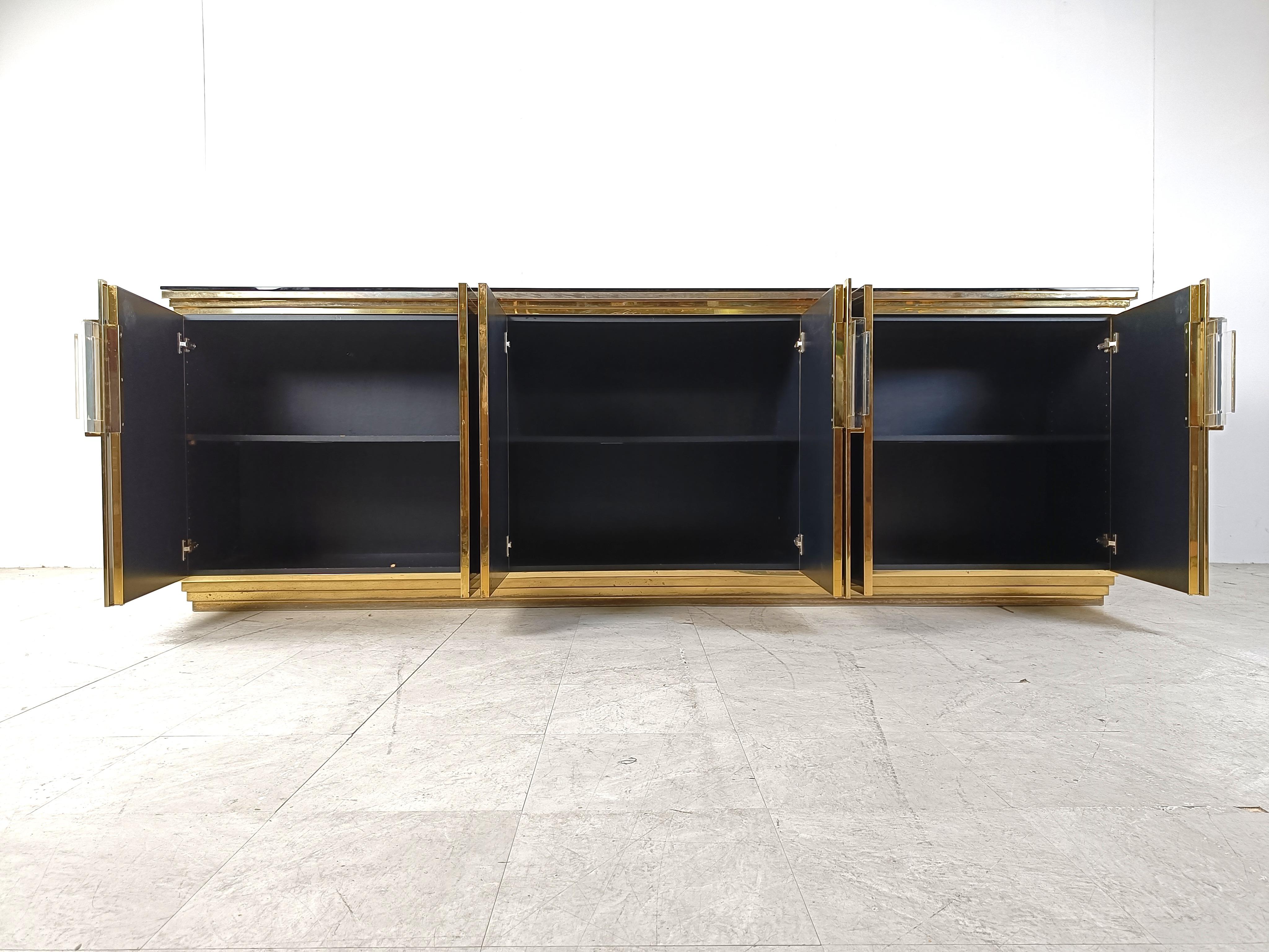 Luxurious black lacquer credenza with brass details and lucite  handles and a black glass top.

The sideboard has 6 doors which reveal a lot of storage space.

Beautiful piece with nice patina on brass.

1980s - France

Dimensions:
Height: