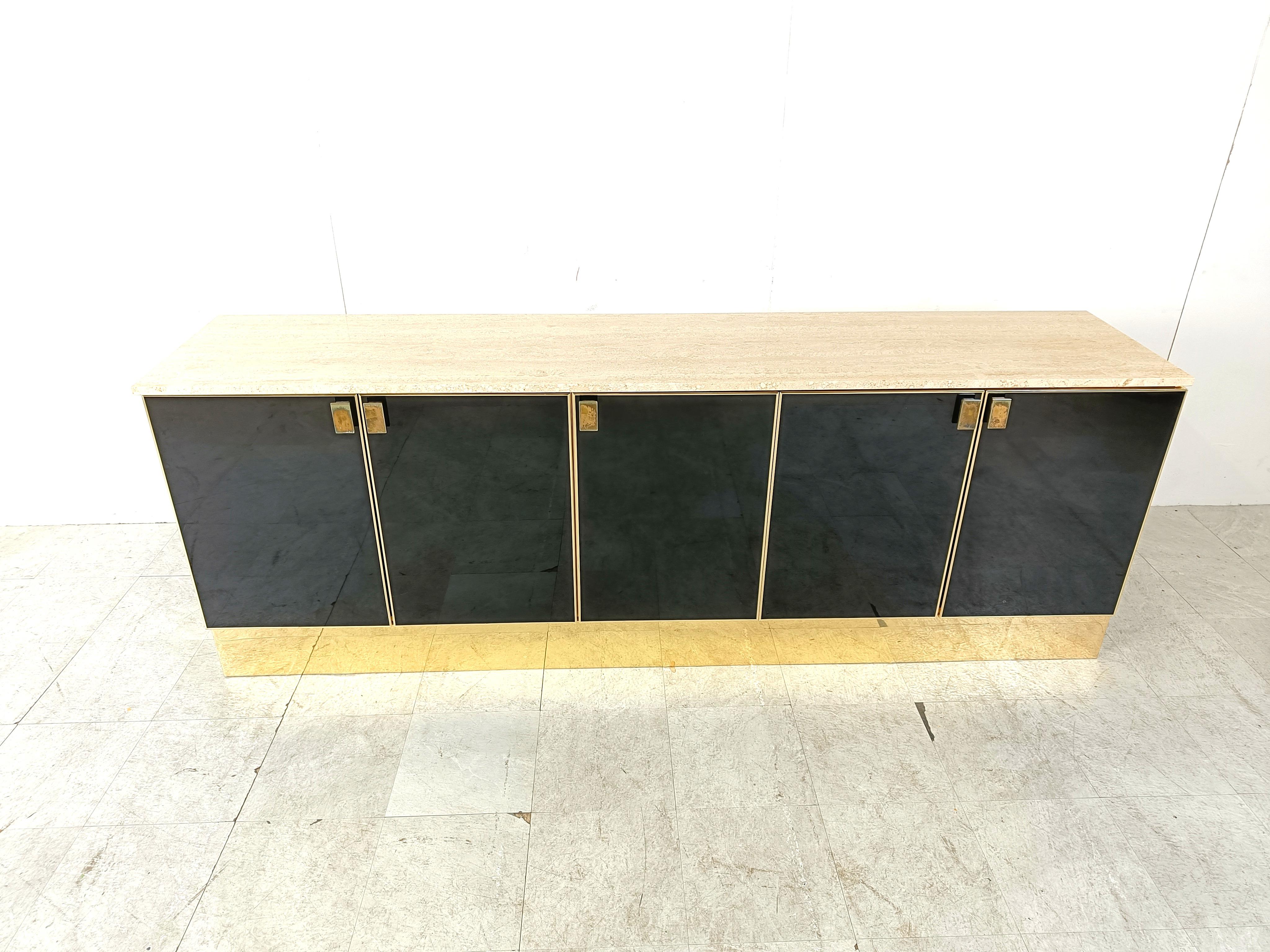 Luxurious black lacquer credenza with brass details and handles and a gorgeous travertine table top.

The sideboard has 5 doors, with two integrated drawers, offering plenty of storage space.

Beautiful piece with normal age related wear.

1980s -