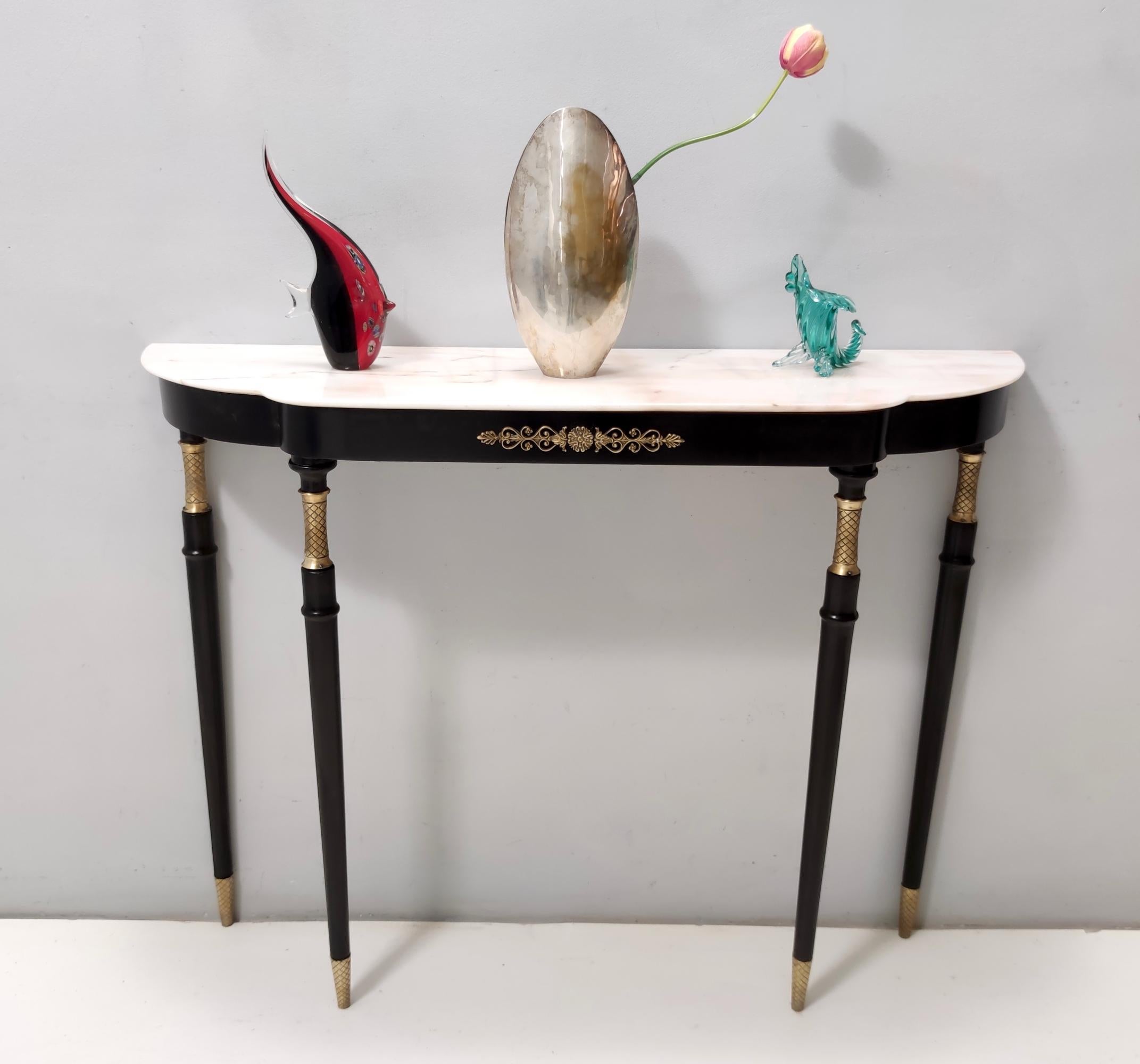Made in Italy, 1950s - 1960s. 
It features a black lacquered beech frame with a Portuguese pink marble top and brass details and feet caps. 
This console might show slight traces of use since it's vintage, but it's been recently restored and
