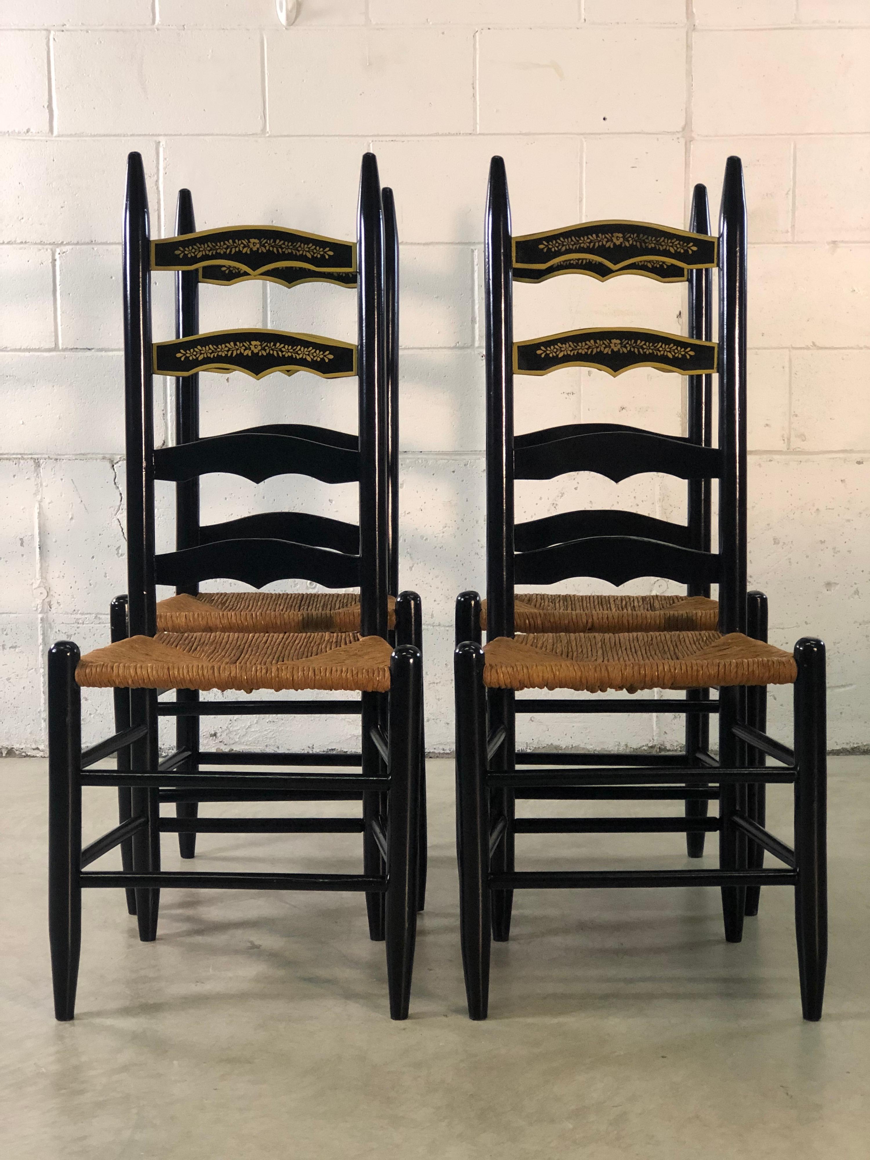 Vintage set of 4 black ladder back dining chairs with rush seats and painted floral accents. Excellent refinished condition.