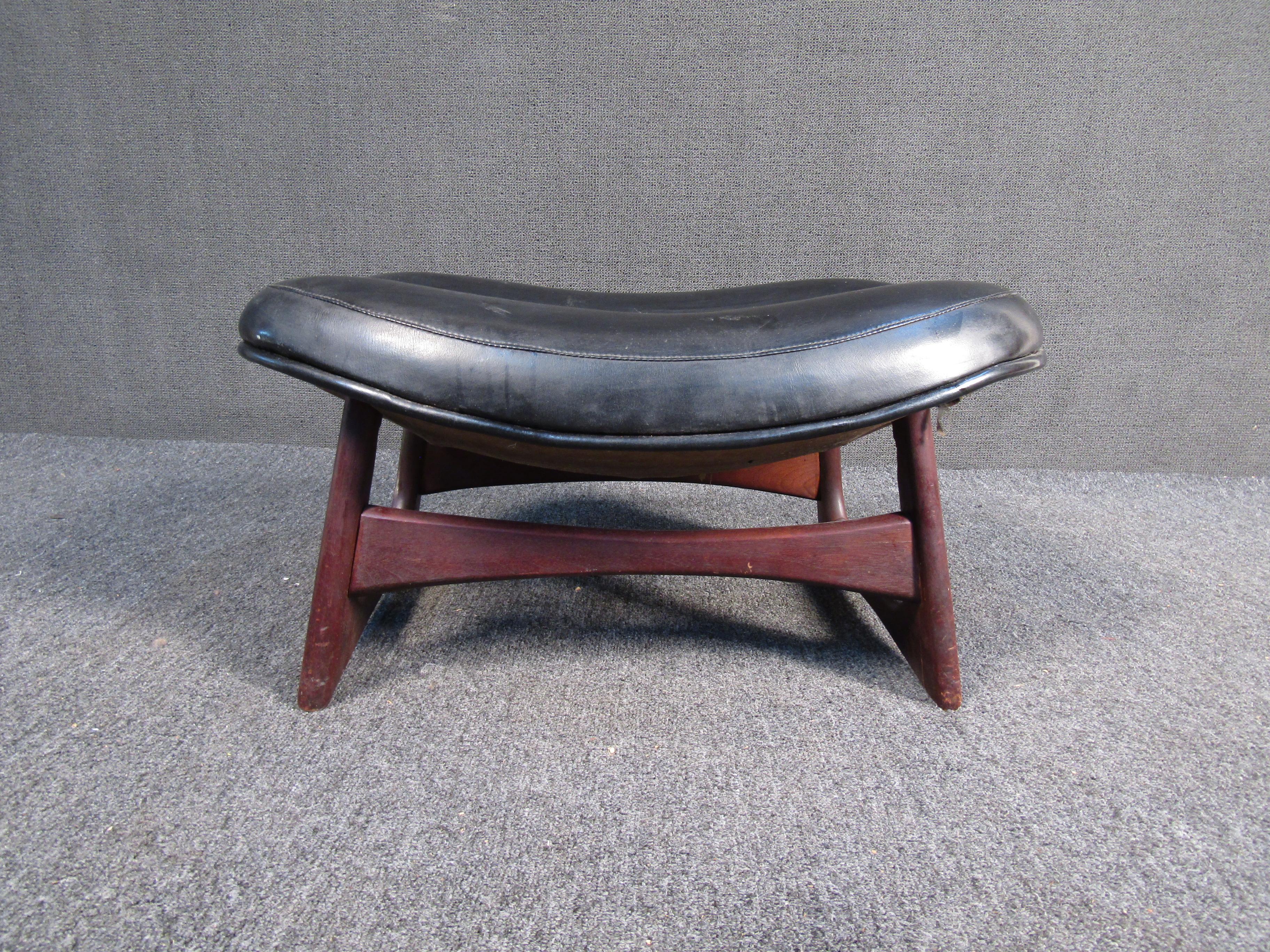 Vintage foot stool ottoman features black leather top and finished wood frame. Unique cross beams connect each leg adding sturdiness and style. The sleek black top is padded for comfort making this Mid-Century stool ottoman the perfect addition to