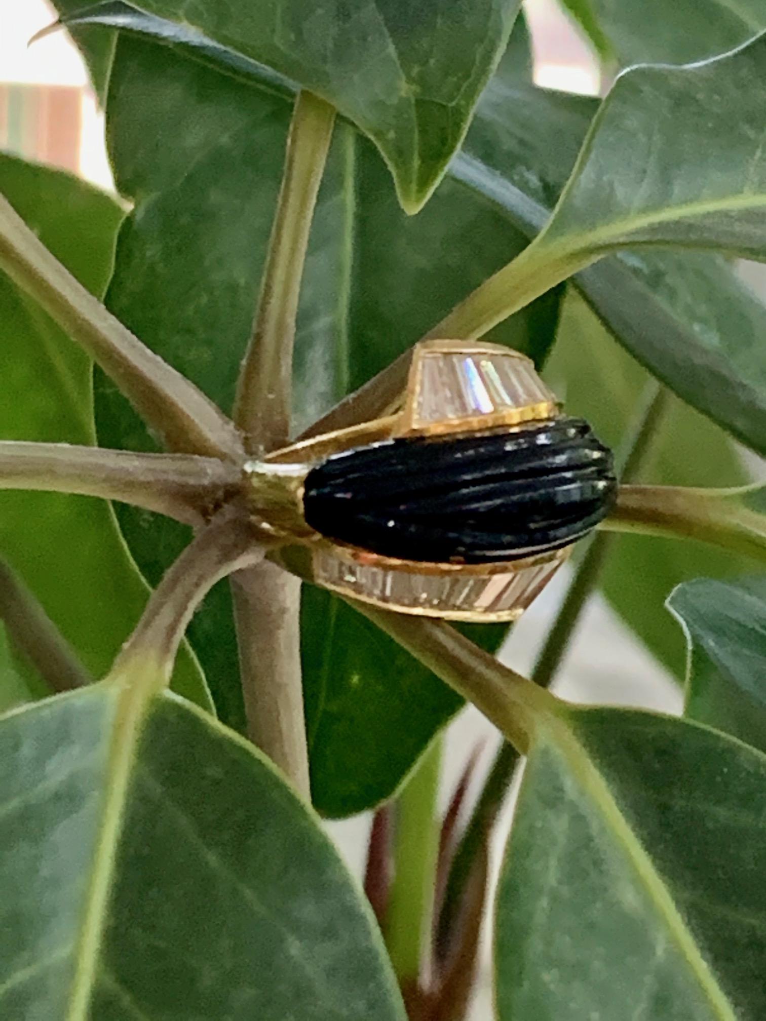 This statement ring features an arc of carved black Onyx wrapping over the top of the band.  On each side of the Onyx is nine baguette Diamonds for a total of 18 stones.  
Color: G/H
Clarity: VS

Size 5 1/2 - This ring can be resized, but G.