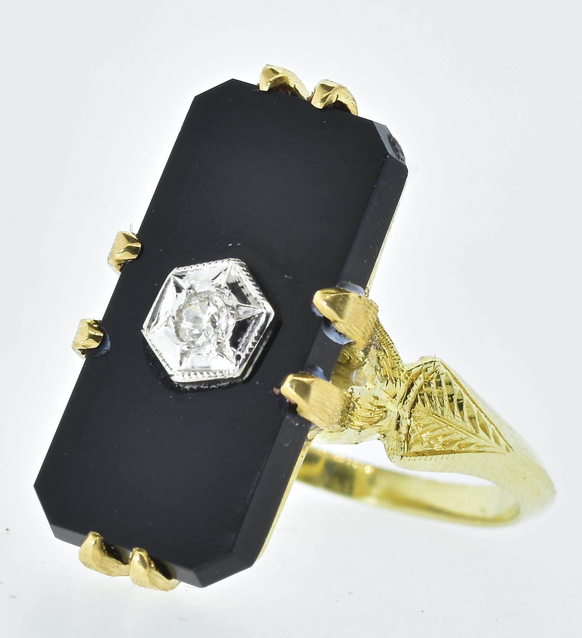 Onyx and diamond vintage yellow gold ring in fine condition centering a prong set rectangular cut black onyx set in the center with a fine white old European cut diamond.  This diamond is set in a white gold star-like bezel surrounded with