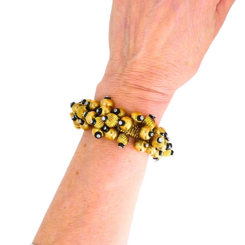 Circa 1950s black onyx and gold bead bracelet made in France.
The bracelet is designed as a Tubogas, decorated with multiple gold beads. Some of the beads are smooth, while others have a spiral texture. Each bead is punctuated with a small black