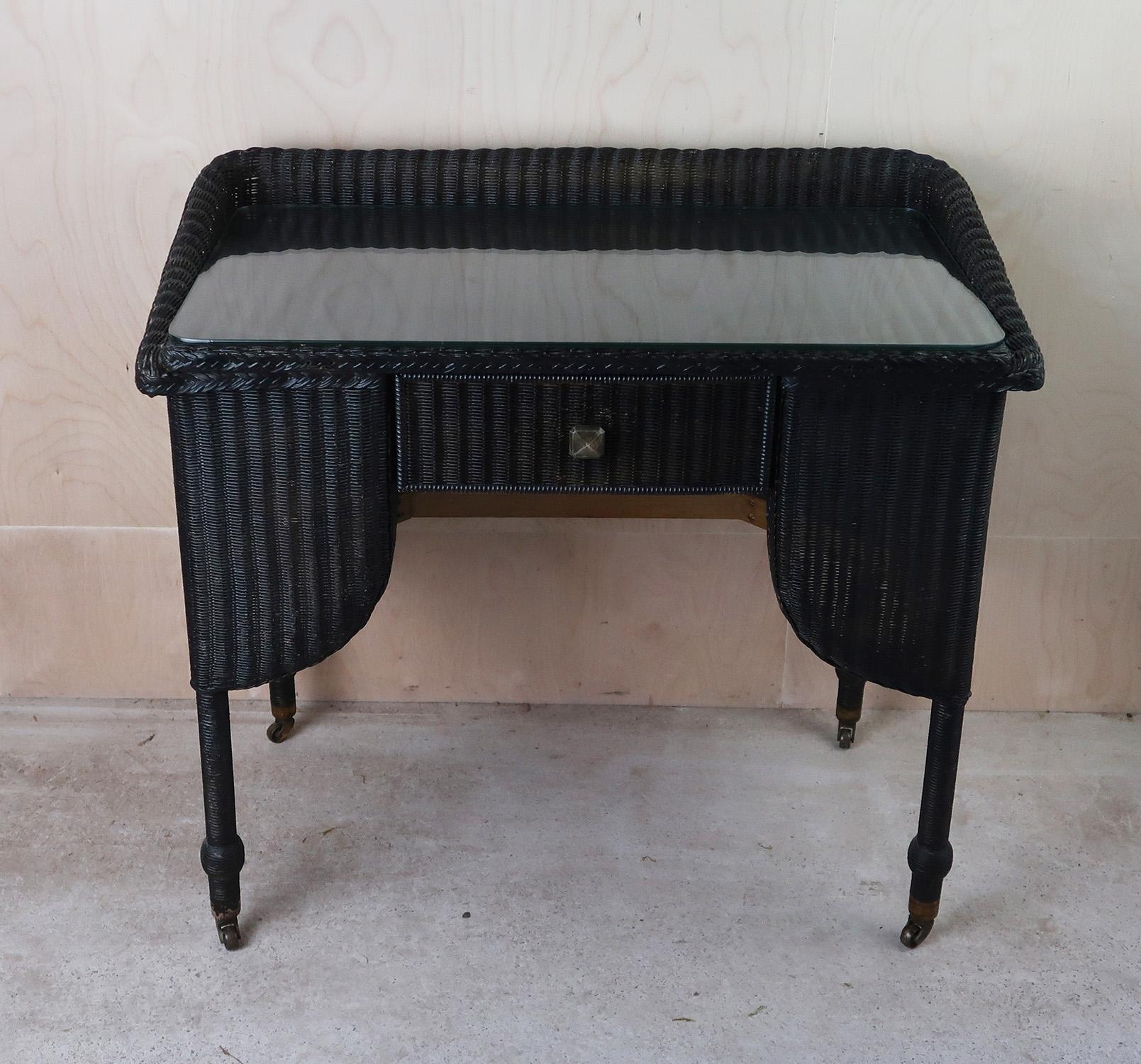 Très élégante table console Lloyds

Peint ultérieurement en noir mat

Peut également servir de coiffeuse ou de bureau

Plateau en verre d'origine. Il est amovible

Sur roulettes d'origine.

Bon état. Il y a 4 petites cassures dans le tissage sur le