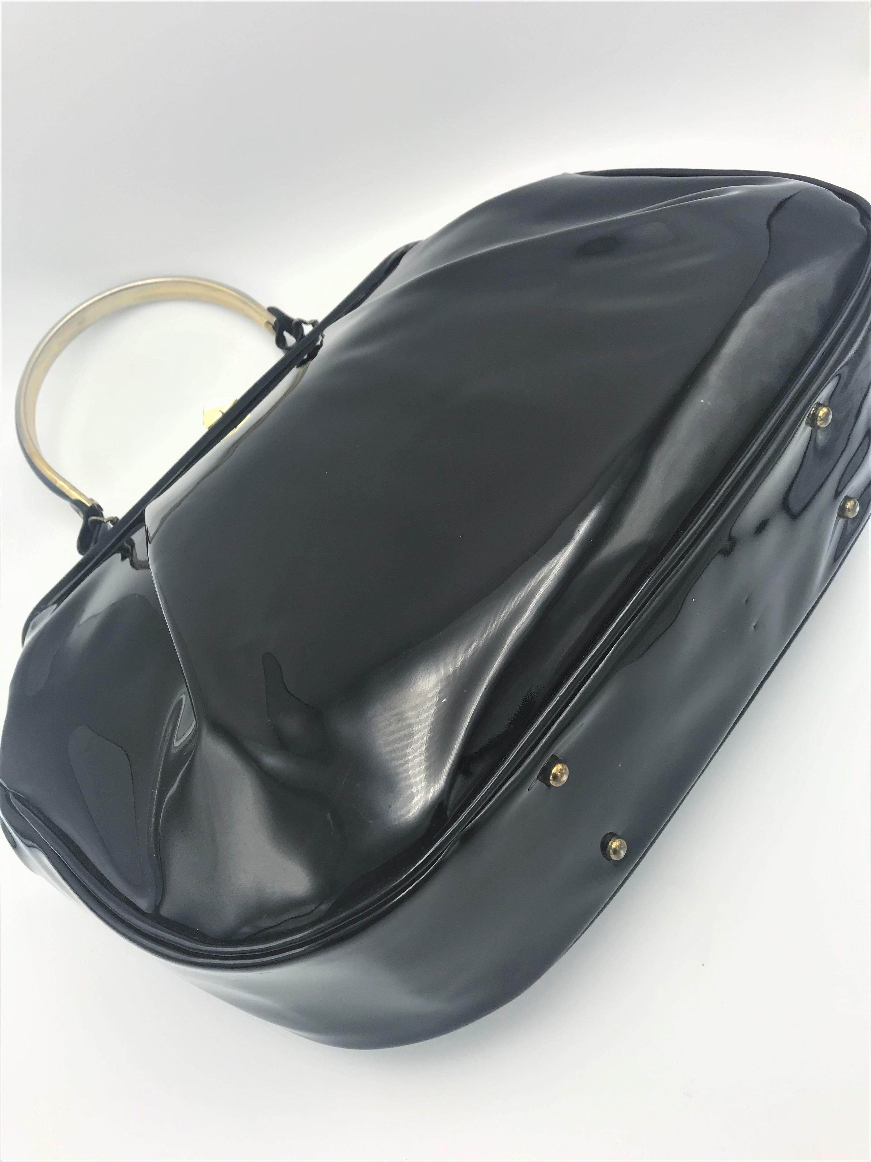 A distinctive black handbag made of beautiful and well-preserved patent leather wich has a handle 30 cm long. The opening is 30 cm wide, the front and back of the bag have a 3 cm deep fold. Lined inside with black-white fabric and a side pocket with