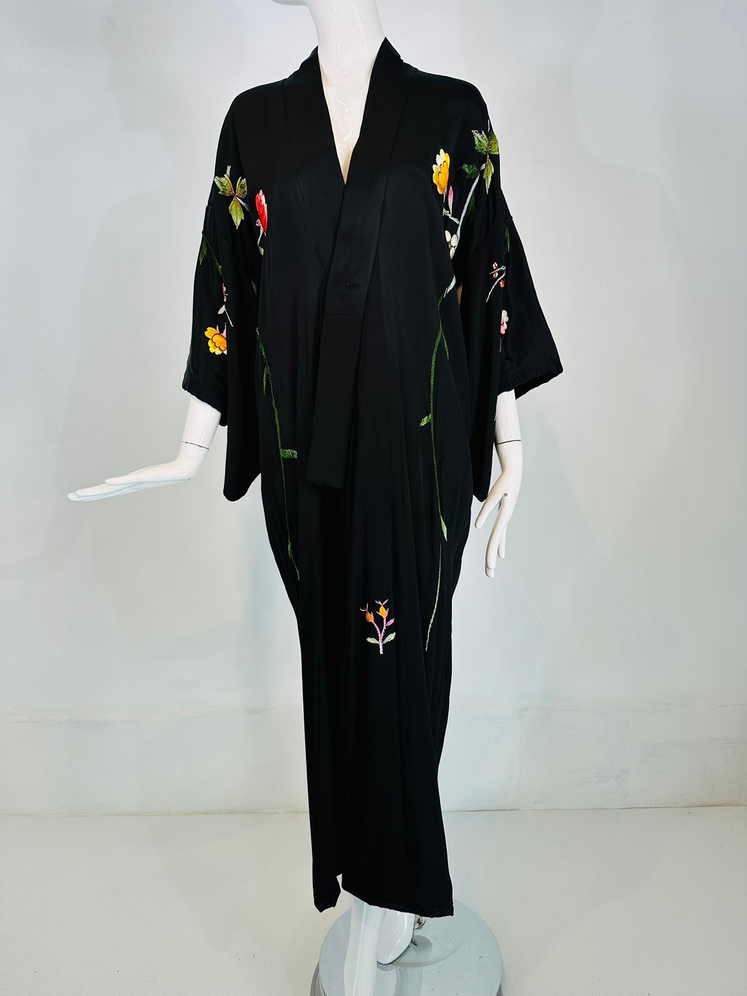 Vintage black rayon heavily floral embroidered kimono robe from the 1930s-40s. Wrap front robe lined in black tissue rayon, with kimono style sleeves that have rolled padded hems. The robe is long. Floral embroidered across front & sleeves. The back