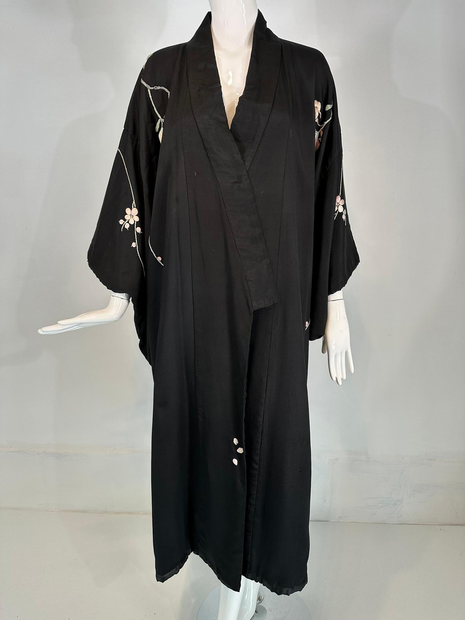 Vintage black rayon pastel floral embroidered kimono robe from the 1930s-40s. Wrap front robe lined in black tissue rayon, with kimono style sleeves that have rolled padded hems. The robe is long. Floral embroidered across front & sleeves. The back