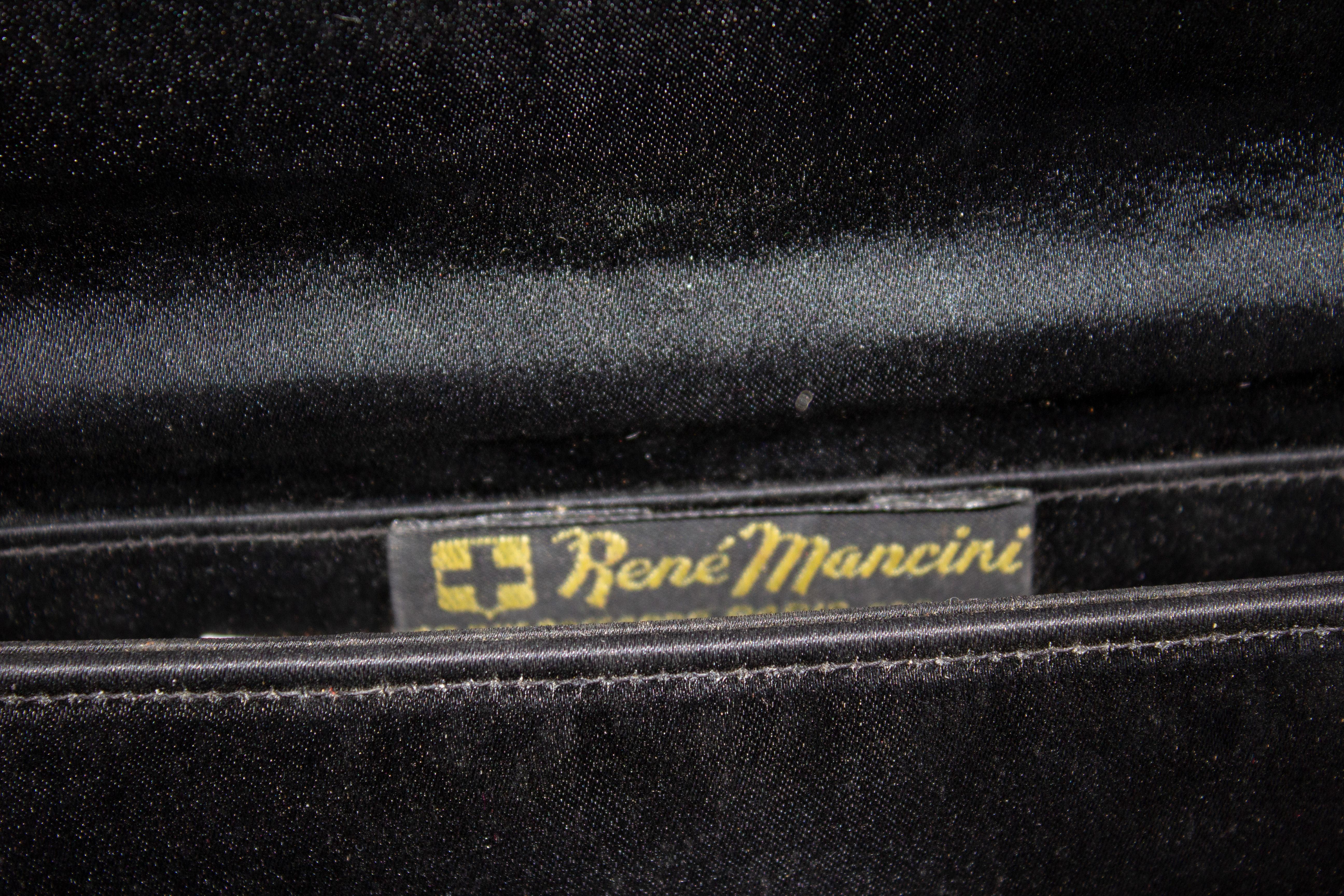Eine schicke Vintage-Abendtasche  von Rene  Mancini. Aus schwarzem Satin mit Überschlag mit Druckknopfverschluss und einer Innentasche. Die Tasche hat attraktive goldene Details auf der Vorderseite und am Griff. Abmessungen: Breite 9'', Höhe 6''