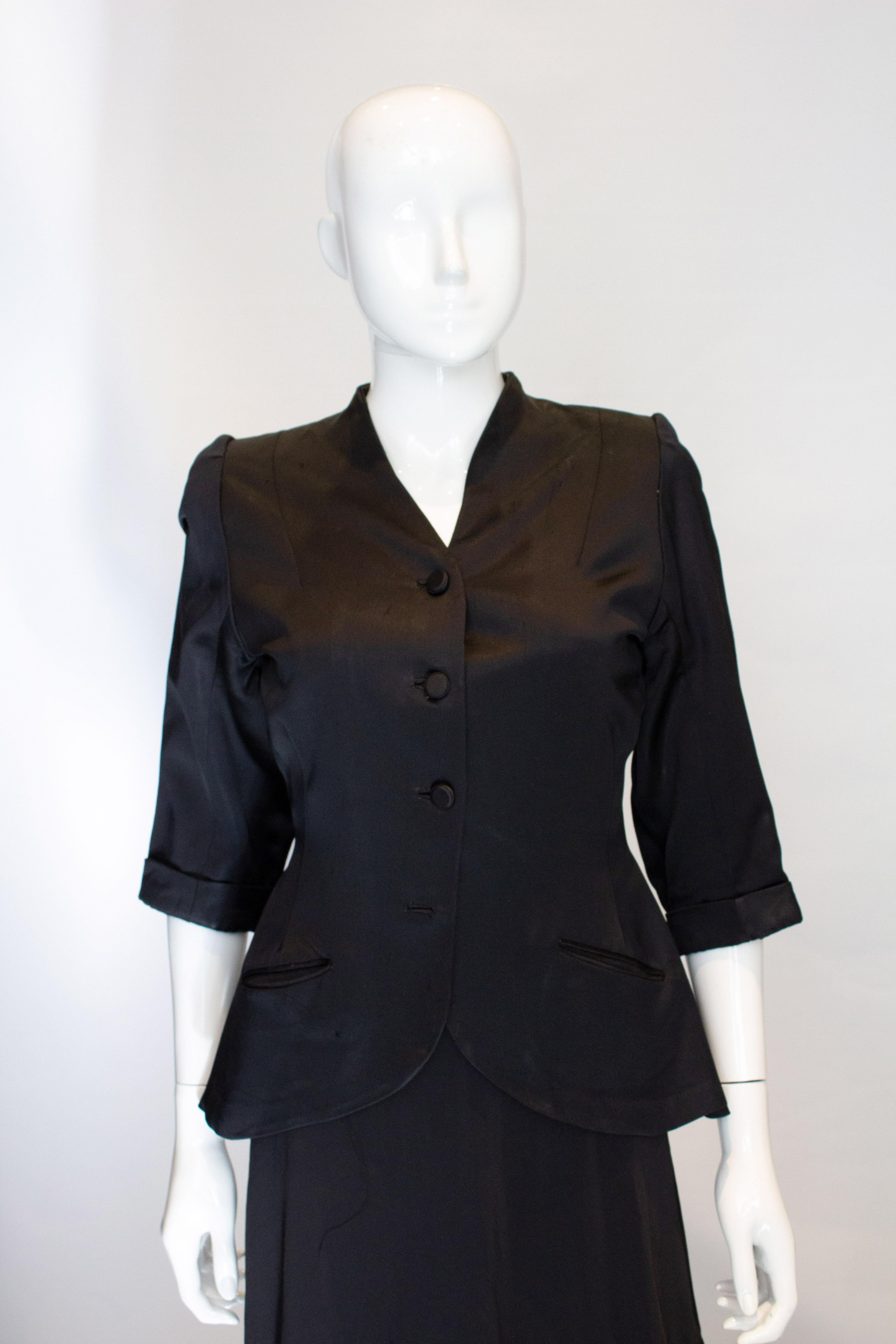 A chic black satin jacket from the 1940s.  The jacket has a v neckline, elbow length sleaves with turn ups, a four button front opening and pockets on either side.
Measurements; Bust 33'', waist 27'', length 25''