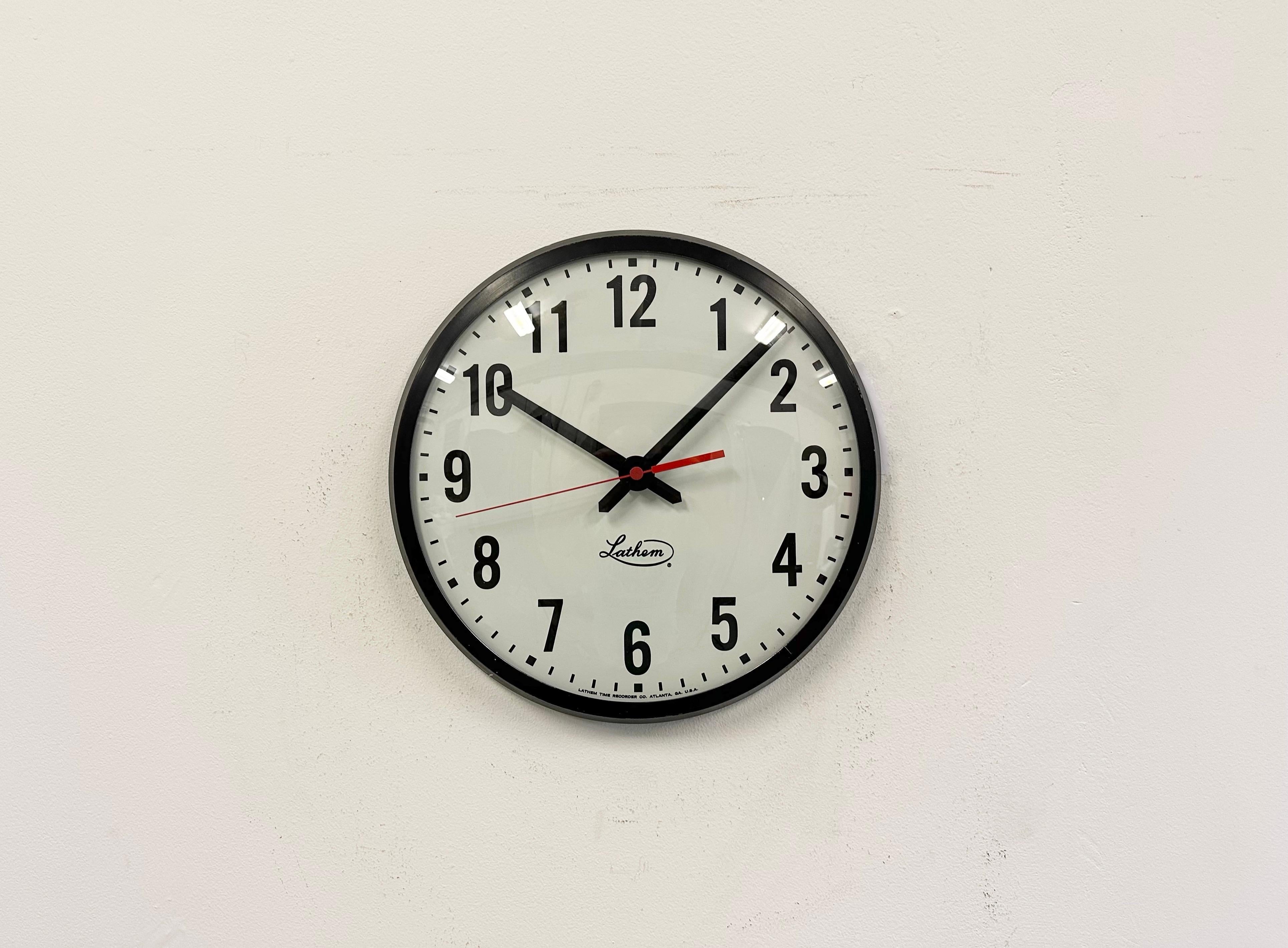 This wall clock was produced by Lathem Time Recorder Co. Atlanta, Georgia in United states during the 1980s. It features a black metal frame, a metal dial and a convex clear glass cover. The piece has been converted into a battery-powered clockwork