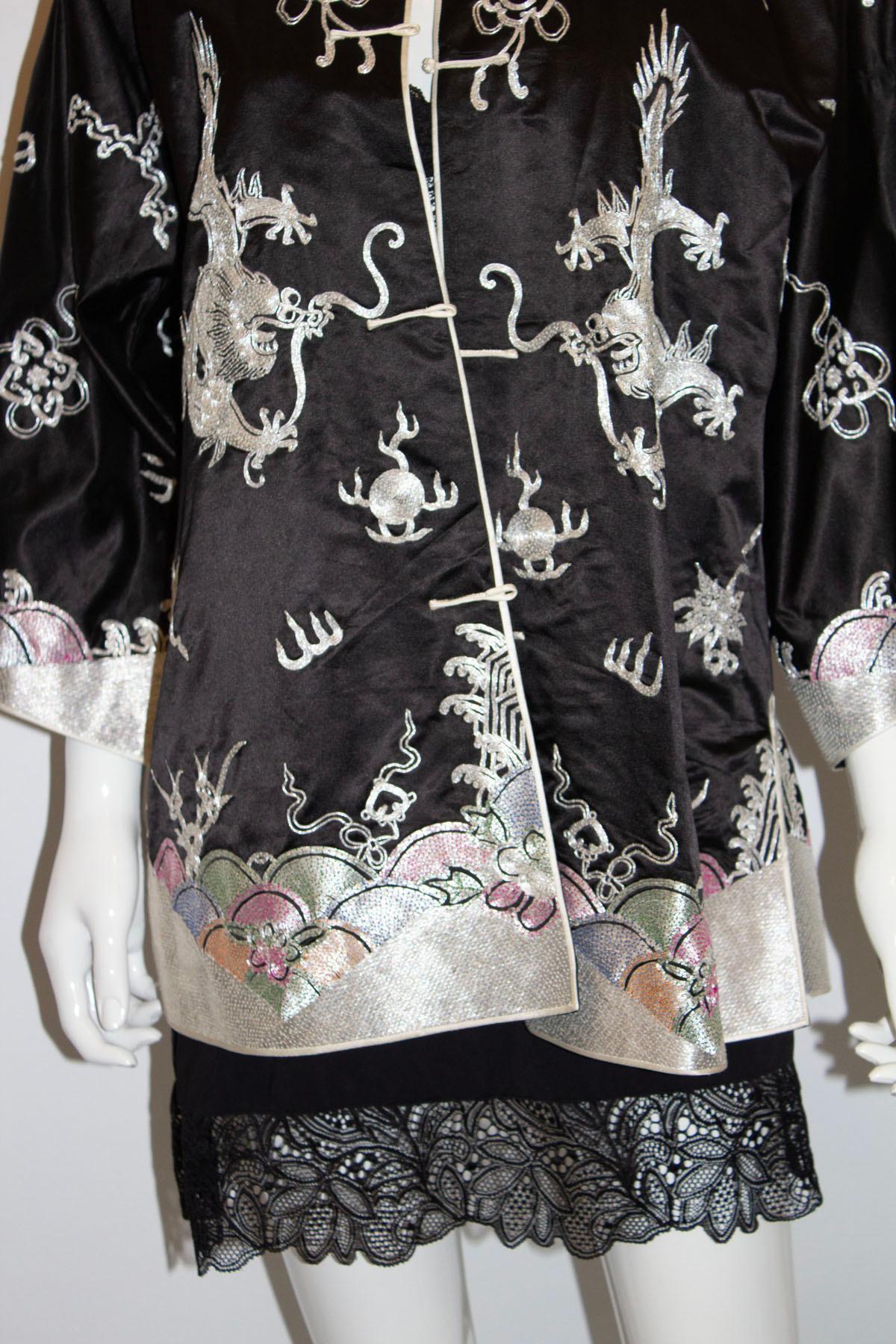 A stunning vintage Chinese evening jacket. In a black silk satin ,the jacket has embroidery decoration in black , silver, pink and green. It has a stand up collar, toggle front fastening and 6'' sits on both sides.  It is fully lined.
Measurements: