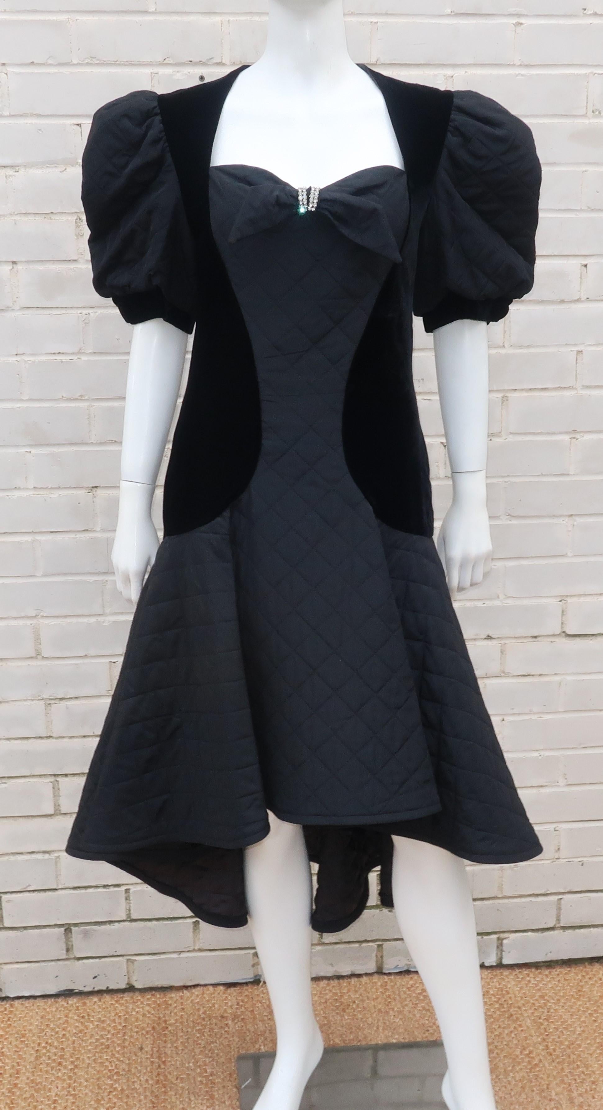 Maryandre Couture of Paris black quilted cocktail dress with velvet side panels, high-low hemline and a rhinestone embellished bow at the bodice.  The 1980's design has a coquettish 1930's aesthetic with a heart shaped neckline and puffed sleeves. 