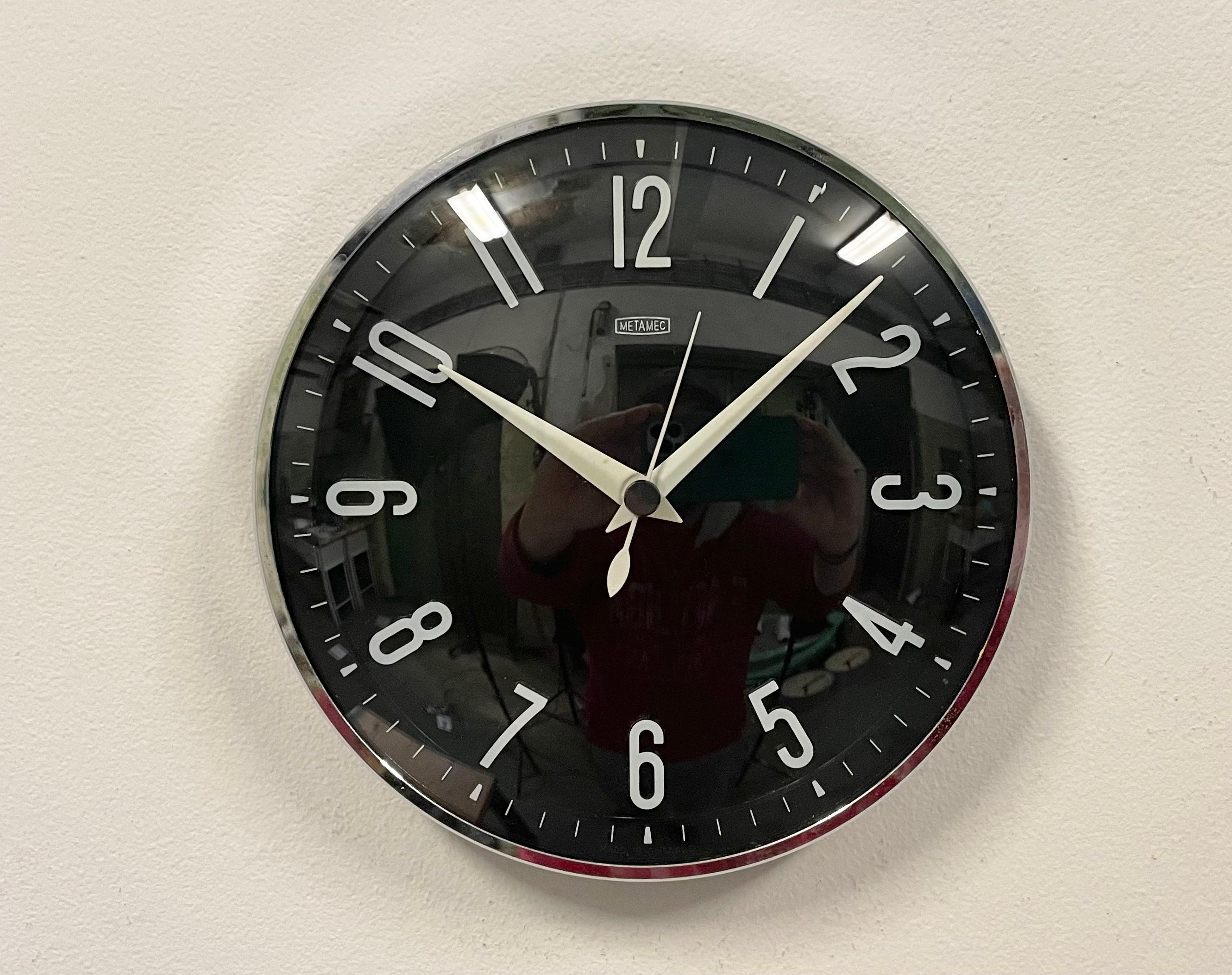 Wall clock produced by Metamec in England during the 1970s. It features a black bakelite clock face with white numerals, a white aluminium hands, chrome -plated frame and a curved clear glass cover. The piece has been converted into a