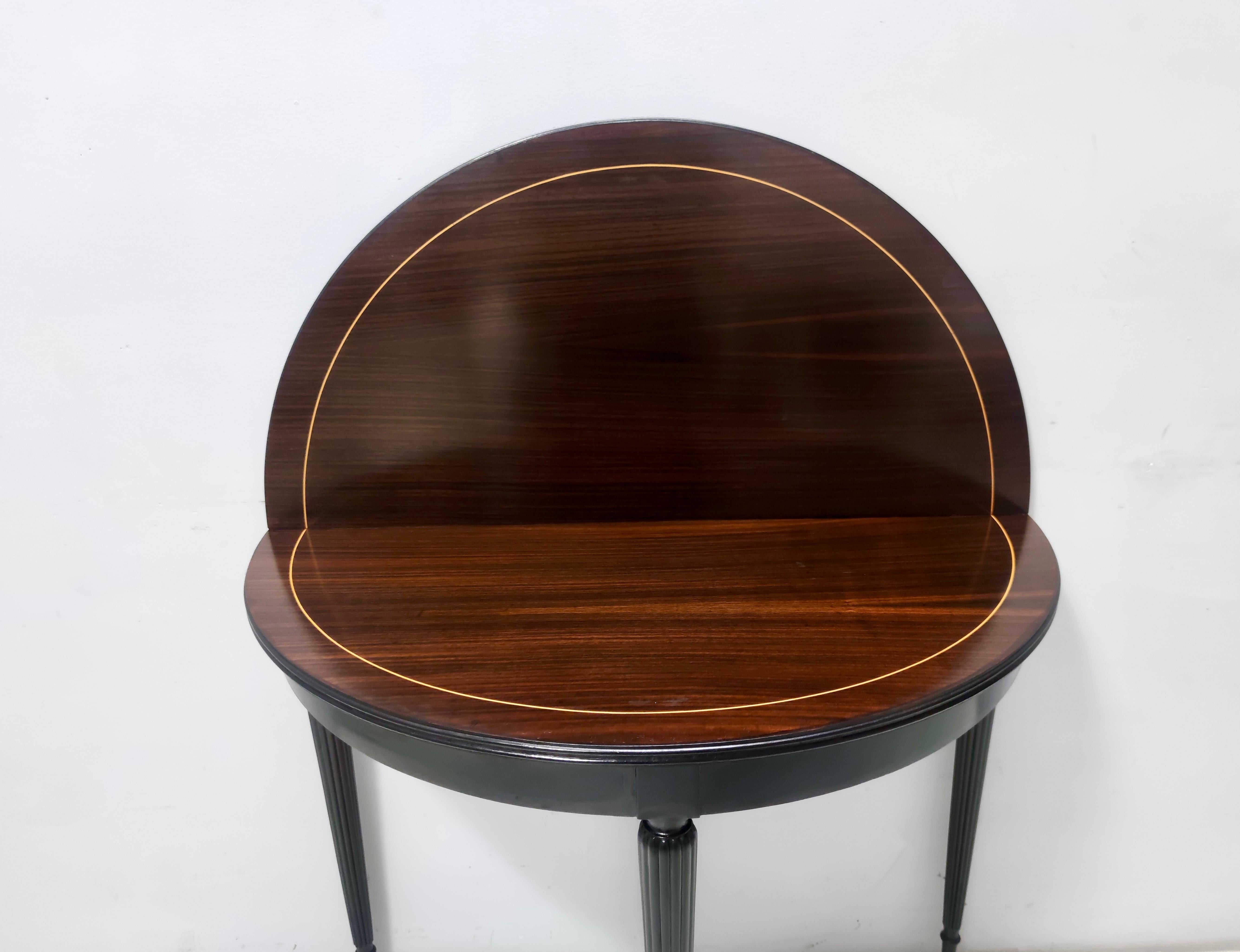 Made in Italy, 1960s. 
It features an ebonized beech and black walnut frame with brass feet caps. 
This round folding table / demilune console table is ascribable to Paolo Buffa and has been recently restored. 
It is a vintage piece, therefore it