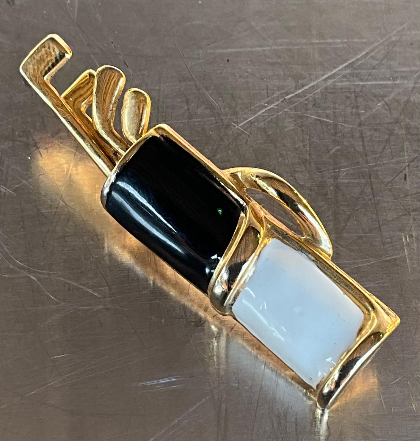 A Vintage Black/White Enamel Golf Bag Brooch is a stylish and playful piece of jewelry, typically designed to evoke themes of sports and leisure. 

The use of black and white enamel in the design suggests a high level of craftsmanship, as enamel is