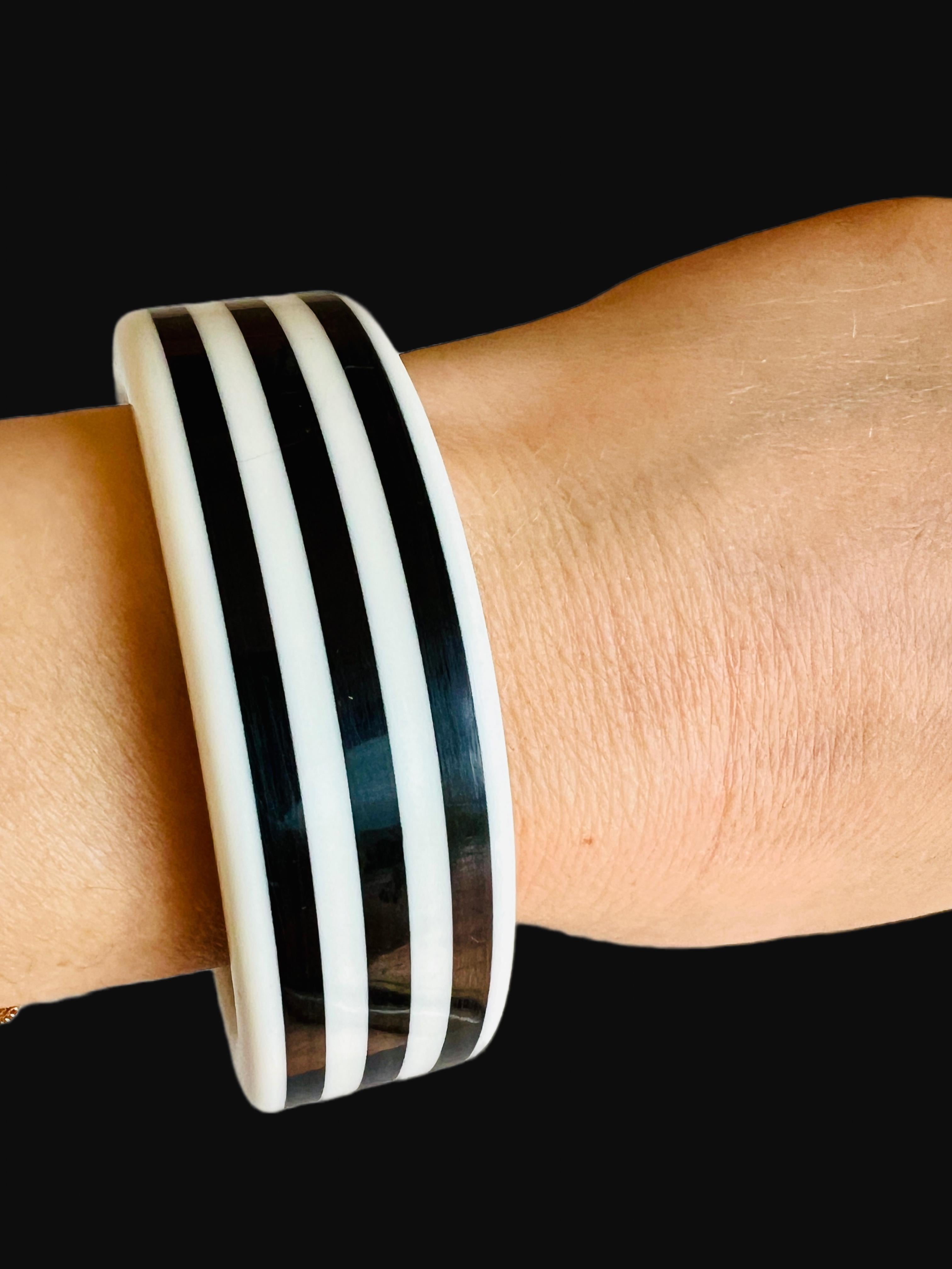This statement bangle bracelet, featuring a striking black and white design, is perfect for adding a touch of sophistication to any outfit. Its wide structure and bold pattern are reminiscent of classic vintage charm, making it an ideal accessory