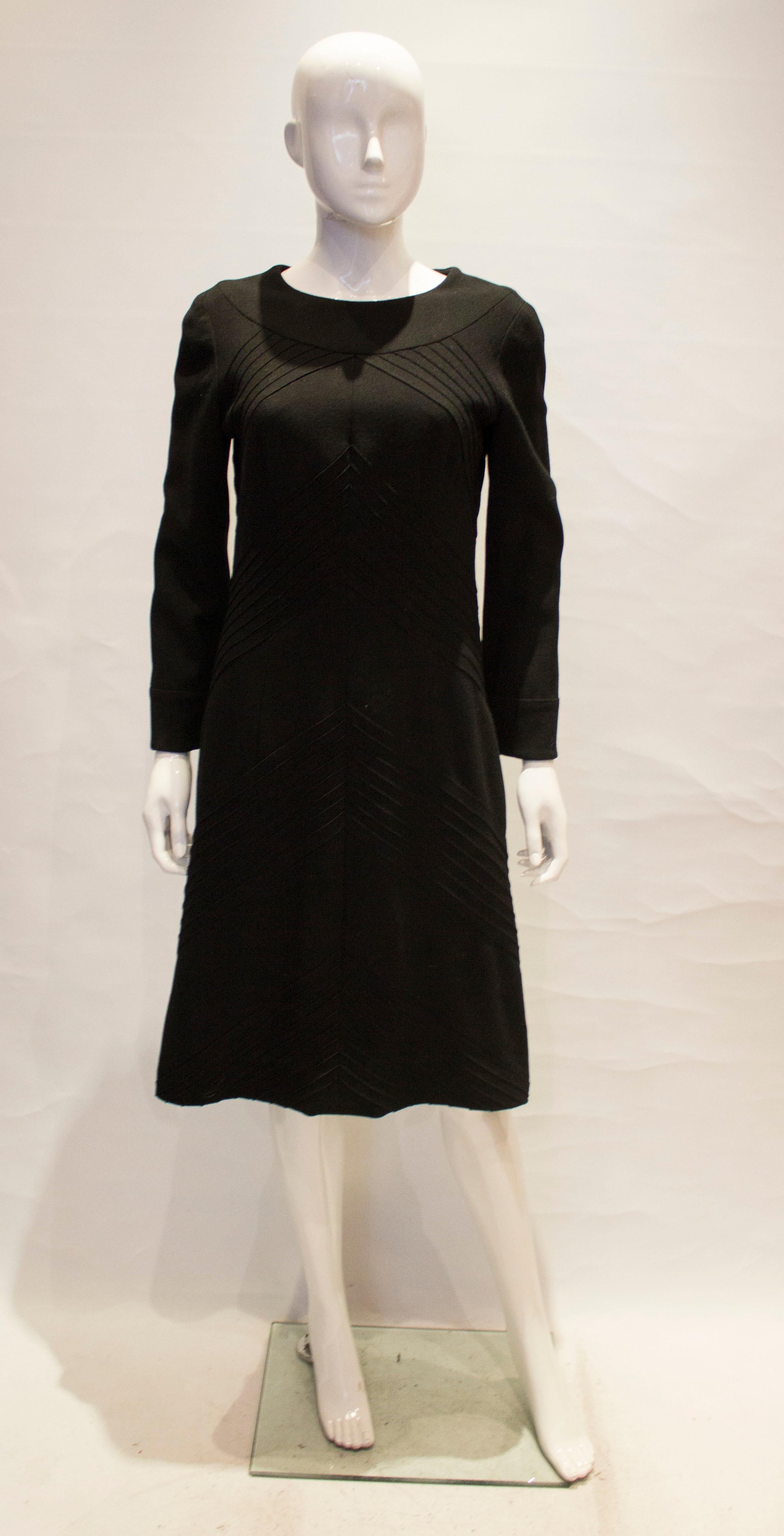 A vintage little black dress by Hartnell. The dress is in a black wool, with a round neckline and stitch detail front and back. It is fully lined and has a central back zip.