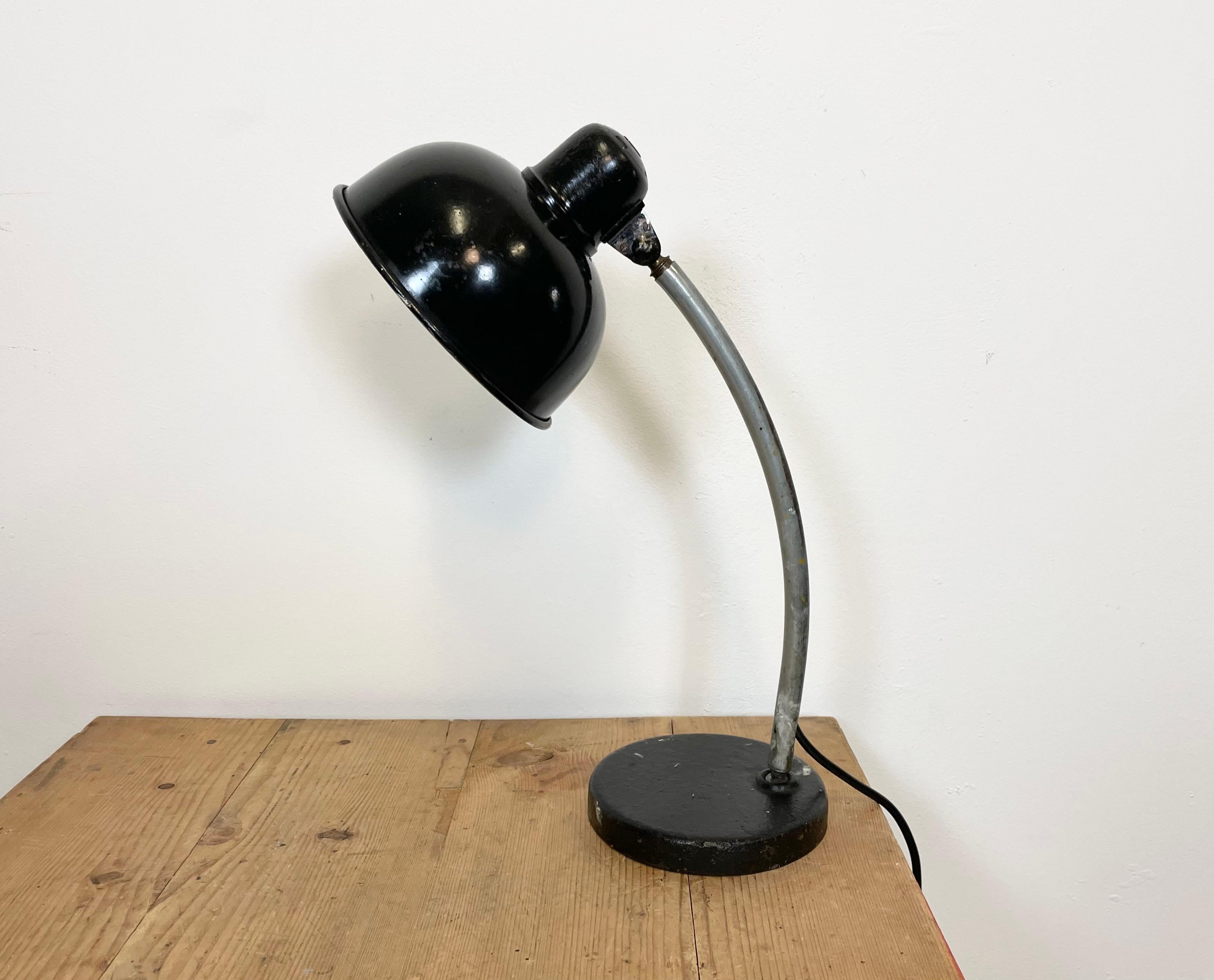 Vintage industrial workshop table lamp with two adjustable joints made in former Czechoslovakia during the 1950s It features an aluminium shade with bakelite top aand a metal arm and base. The original socket requires standard E27/E26 lightbulbs.