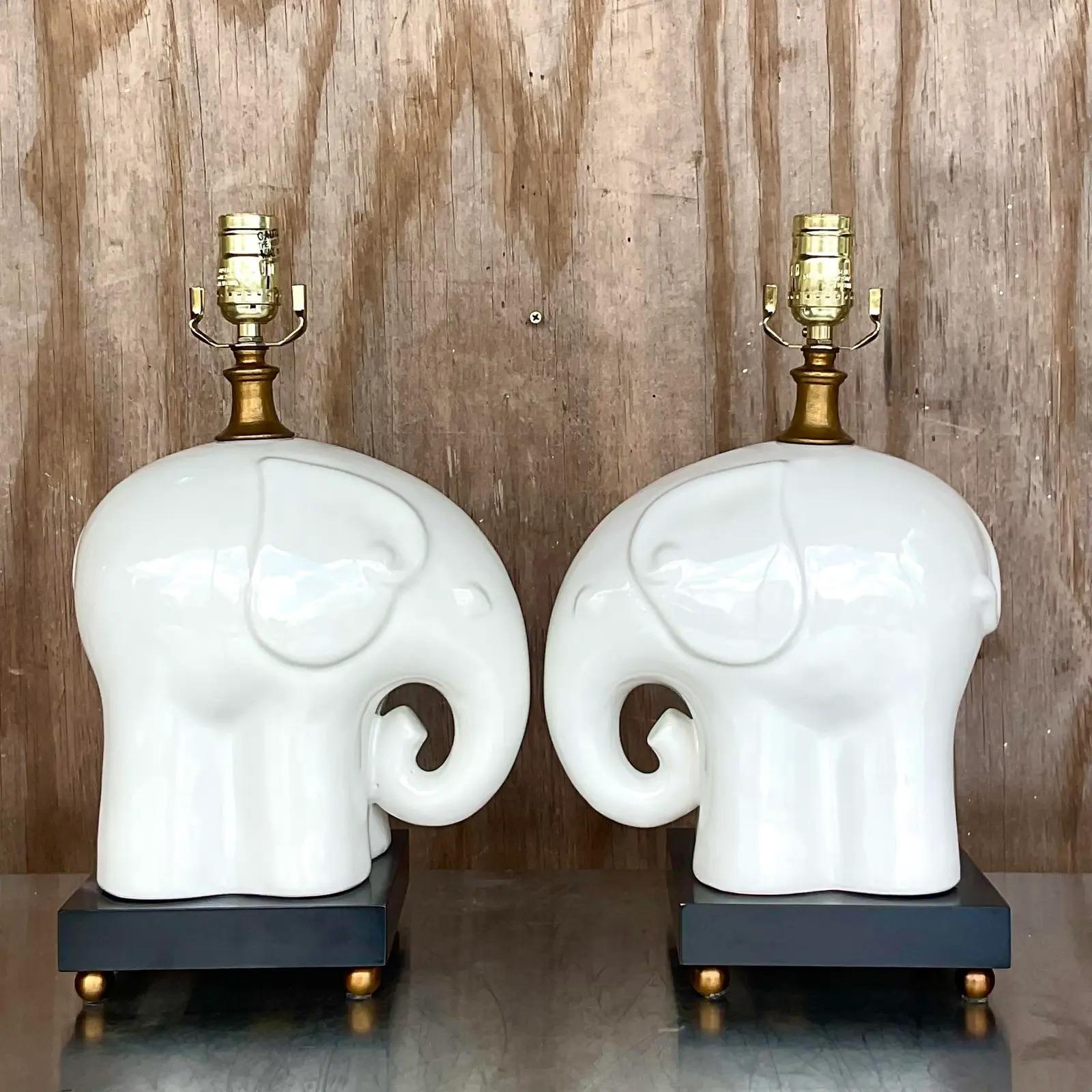 Fantastic pair of vintage glazed ceramic table lamps. Beautiful Blanc De Chine elephants on a contrasting black pedestal. Trunks up for good luck! Acquired from a Palm Beach estate.