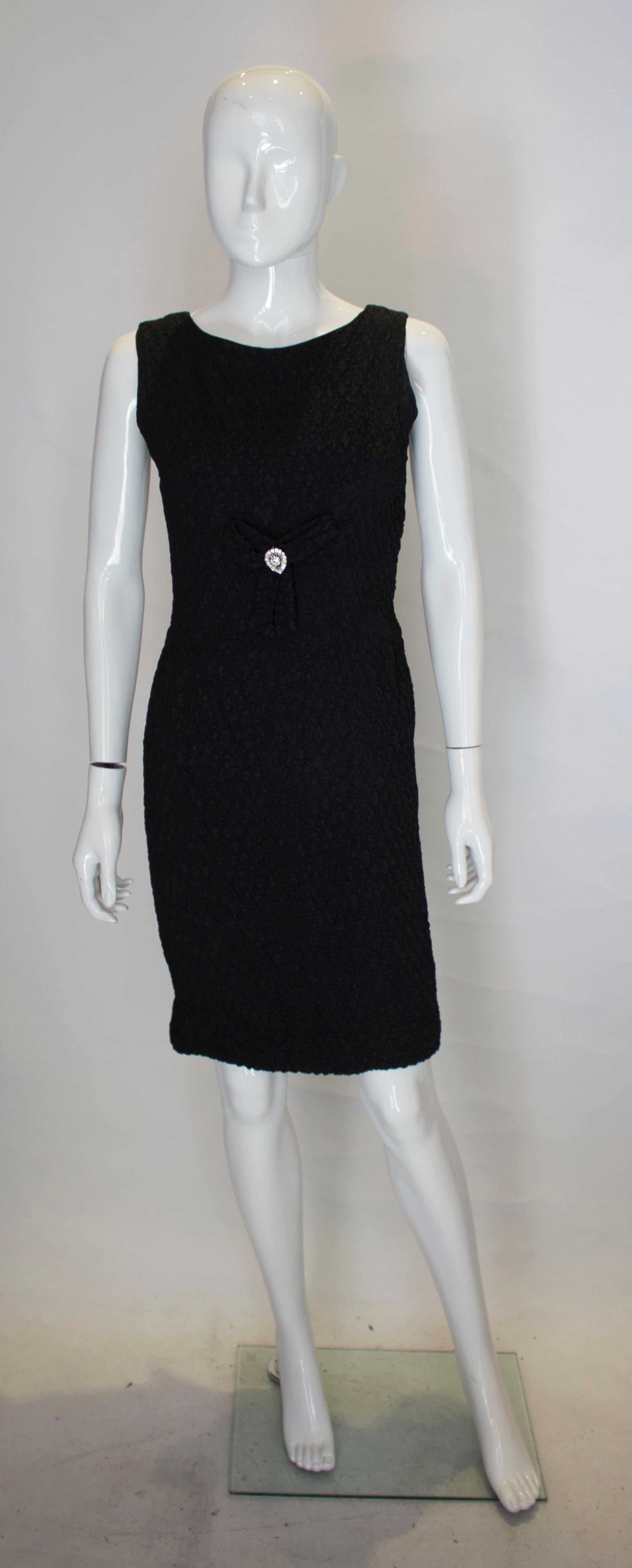 A chic vintage little black dress by Blanes of London. The dress is  in a wonderful puckered  fabric and has a bow and diamante detail at the front.  It has a back zip below the waist and button back fastening above the waist.