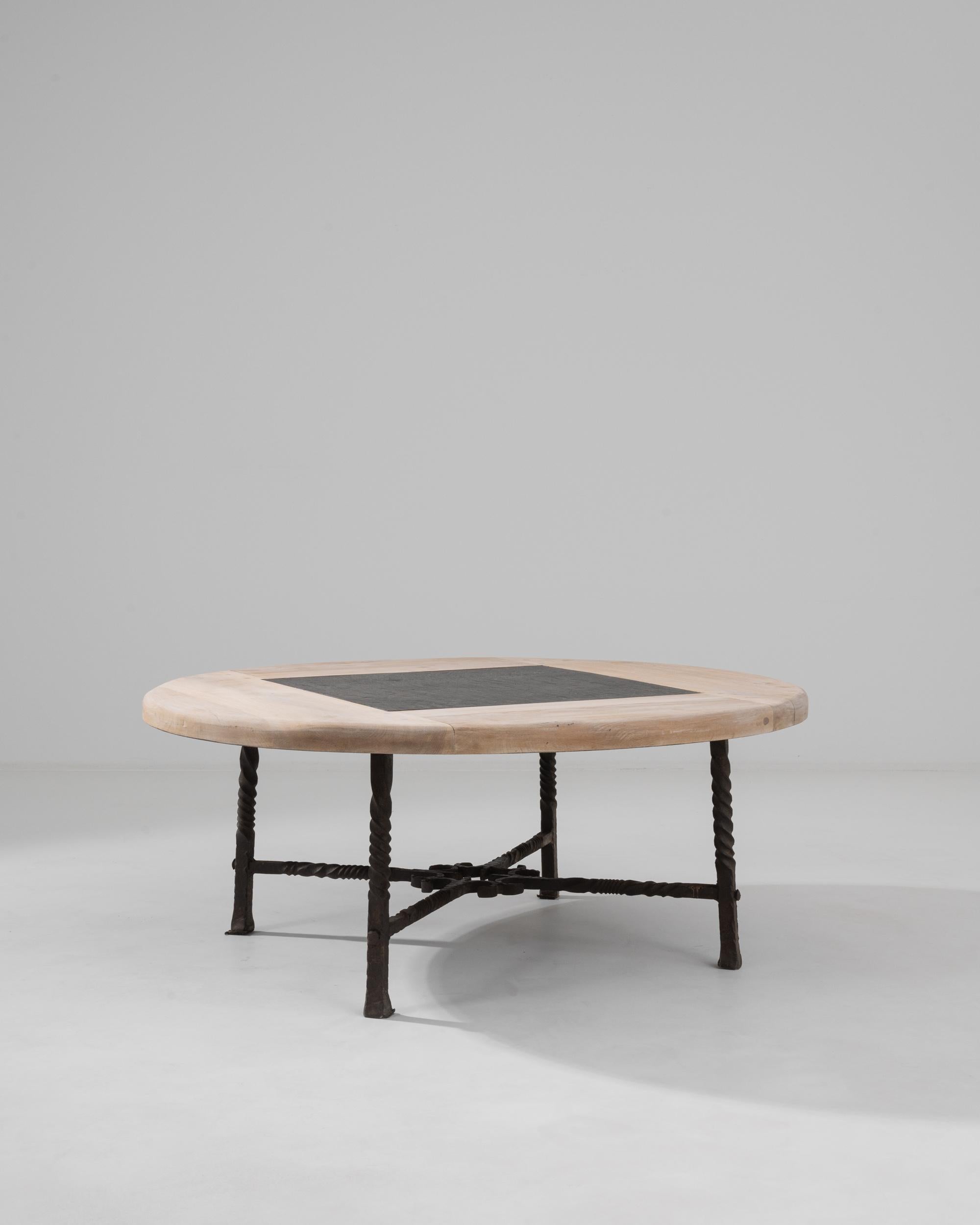 A bleached oak coffee table with an inset stone top produced in France in the 1960s. This low table is designed in a rustic vein of the mid-century modern, the simple round shape is paired with elemental textures of oak, wrought iron and stone. The