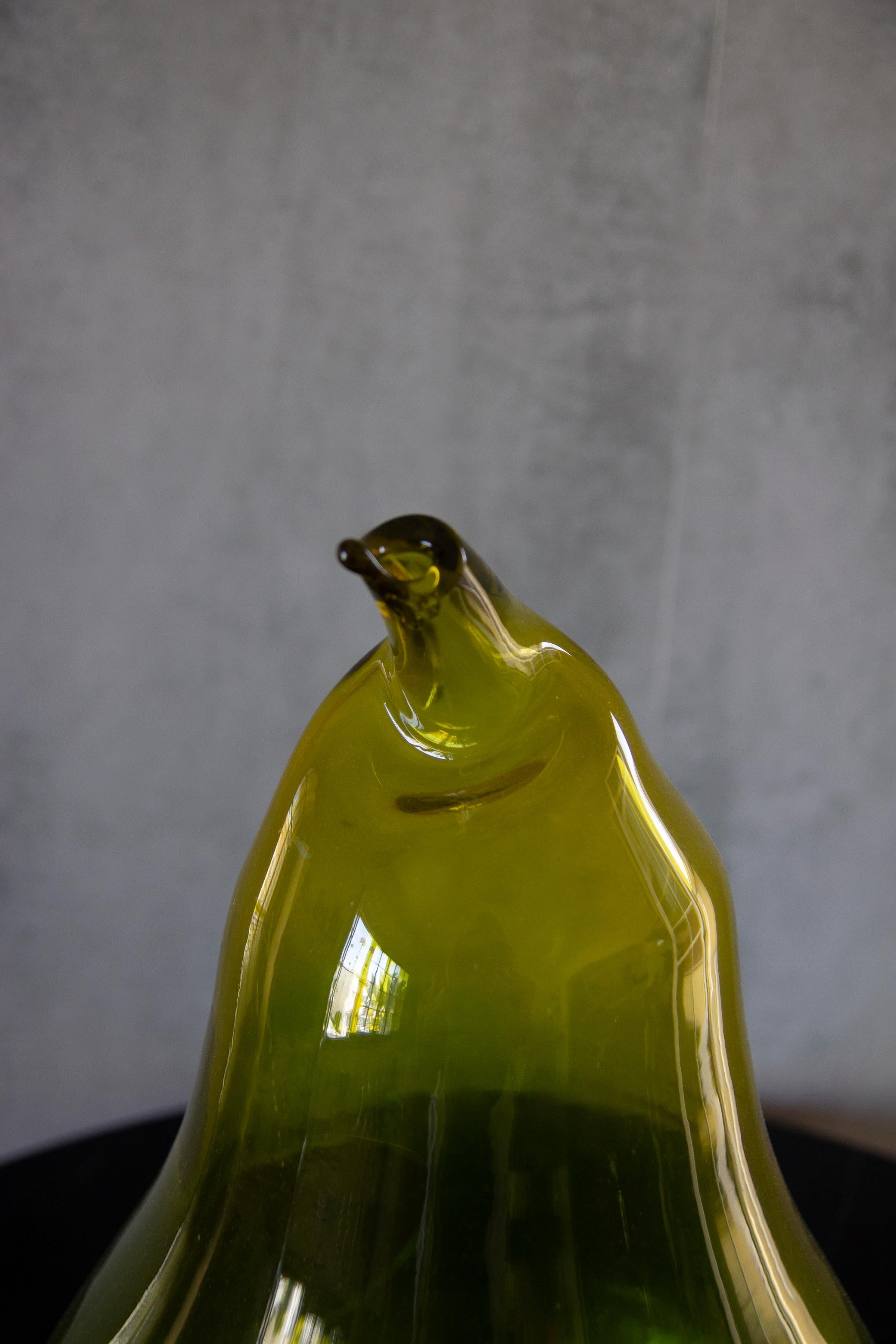 Hand blown green and amber glass shape like a pear with an opening in the middle and also at the end of the stem. 
Unique and delicate sophisticated sculpture. 
It will add some color to your living spaces.