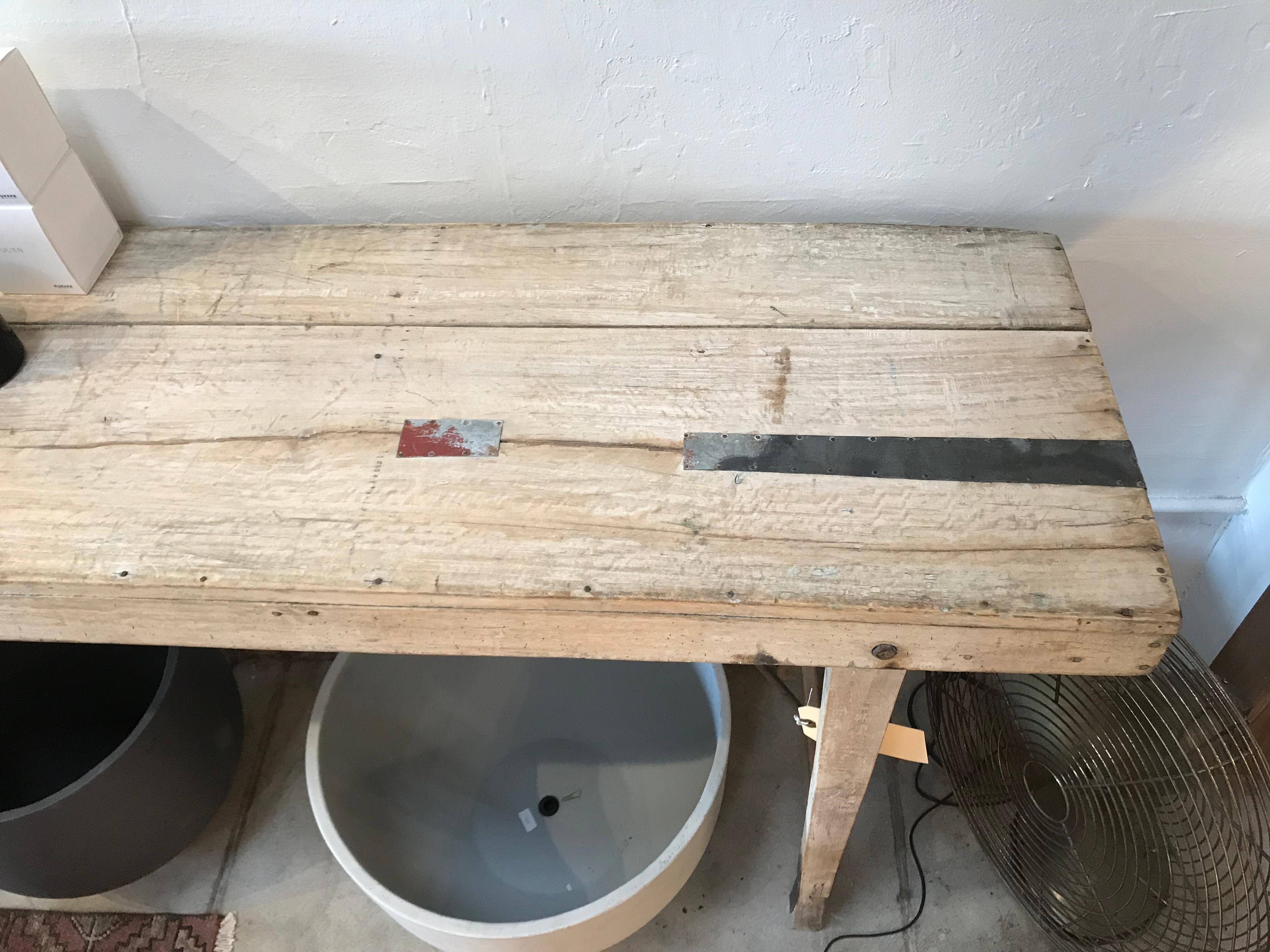 Offered is a vintage light wood Industrial style work table that is great for a entry or console table. The legs fold inward and there is a lot of Patina and beautiful wear on this old piece. There are metal patchwork accents on the top and legs of